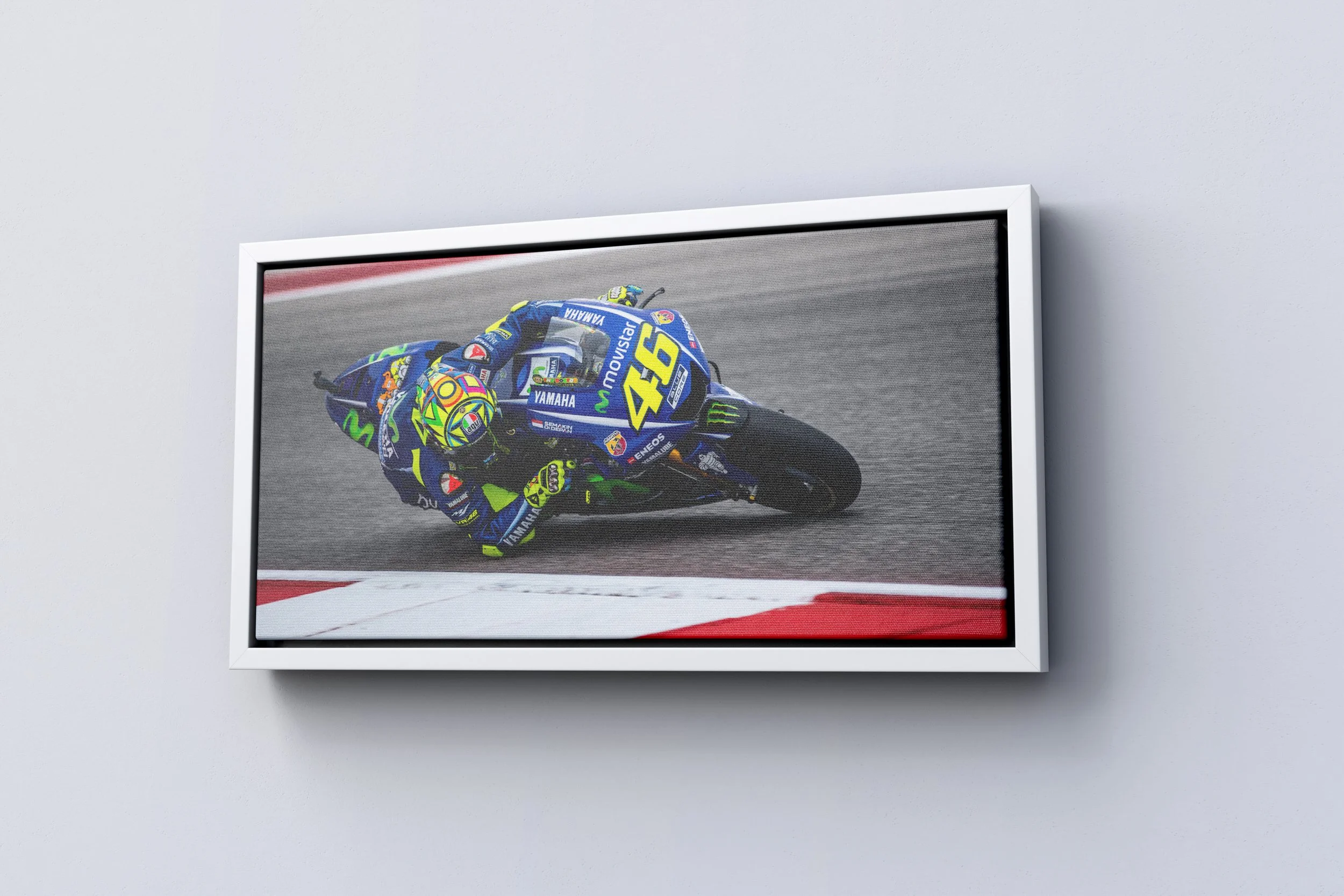 Framed photograph of a motorcycle racer leaning into a turn on a racetrack, wearing a colorful helmet and racing suit, with a Yamaha motorcycle numbered 46.