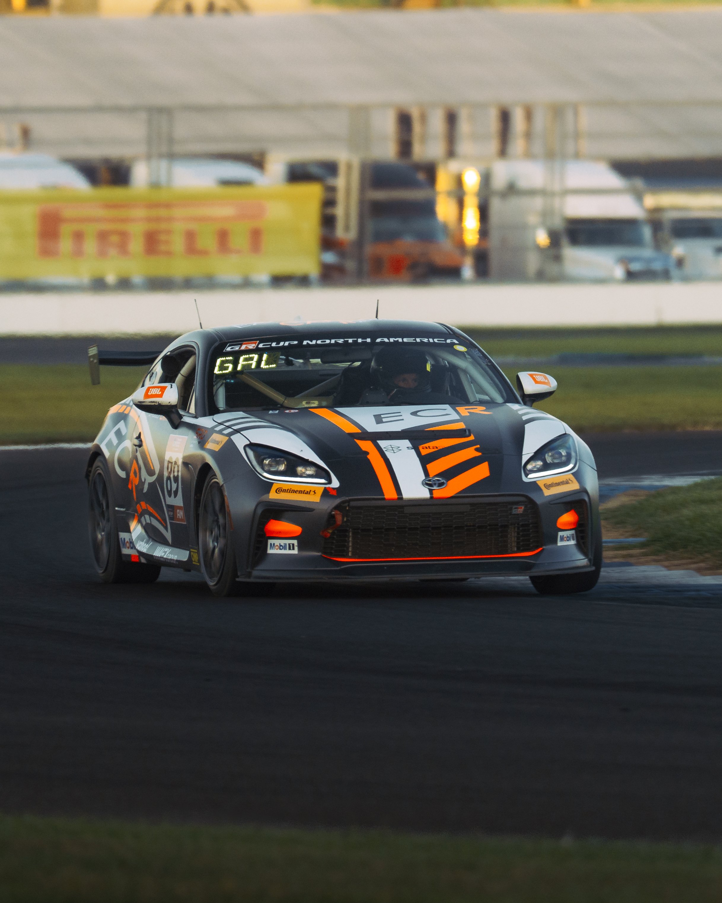 A race car on a track, decorated with sponsor logos and decals, moving at high speed during a race.