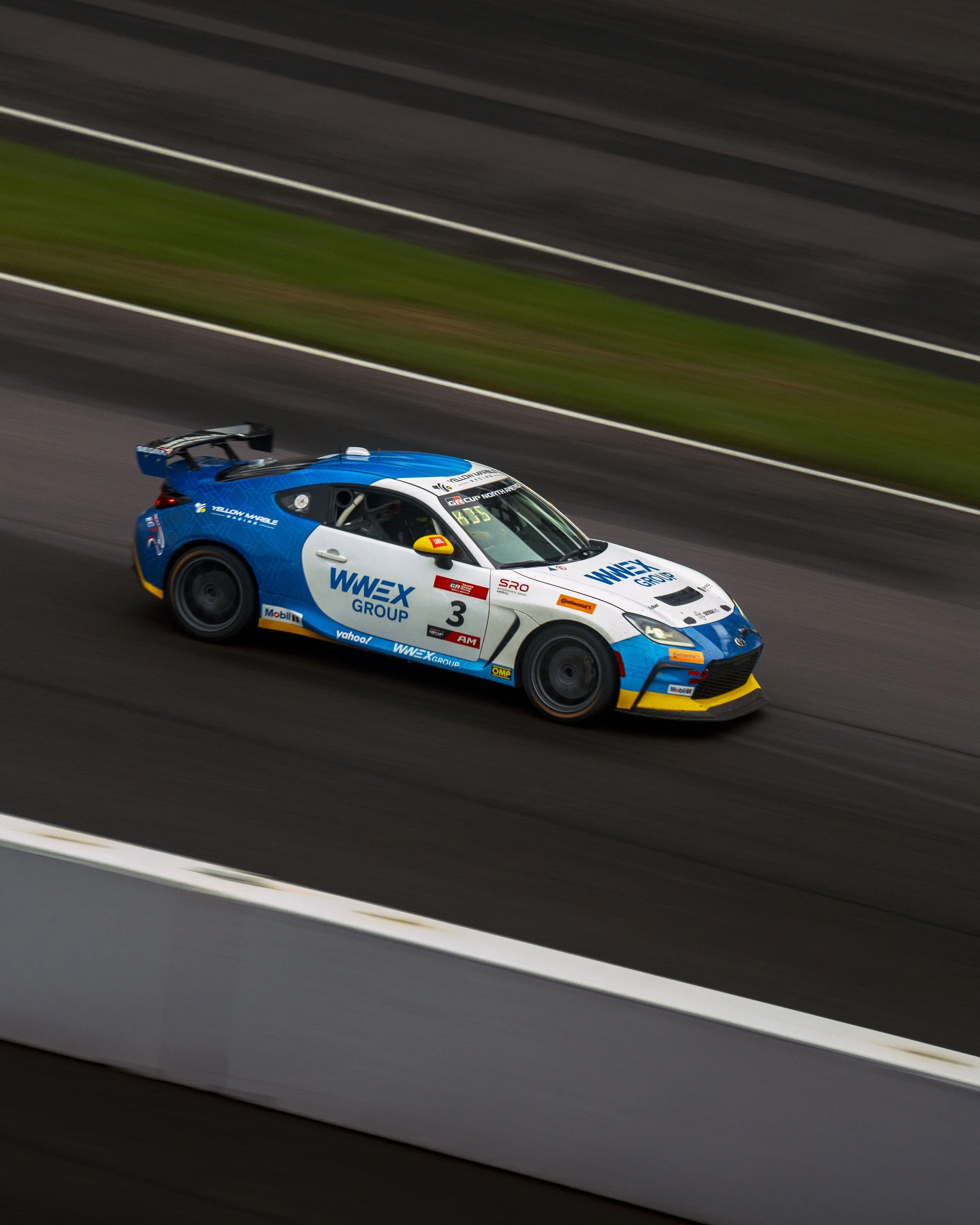 A racing car on a track, colored blue, white, and black with various sponsor logos.
