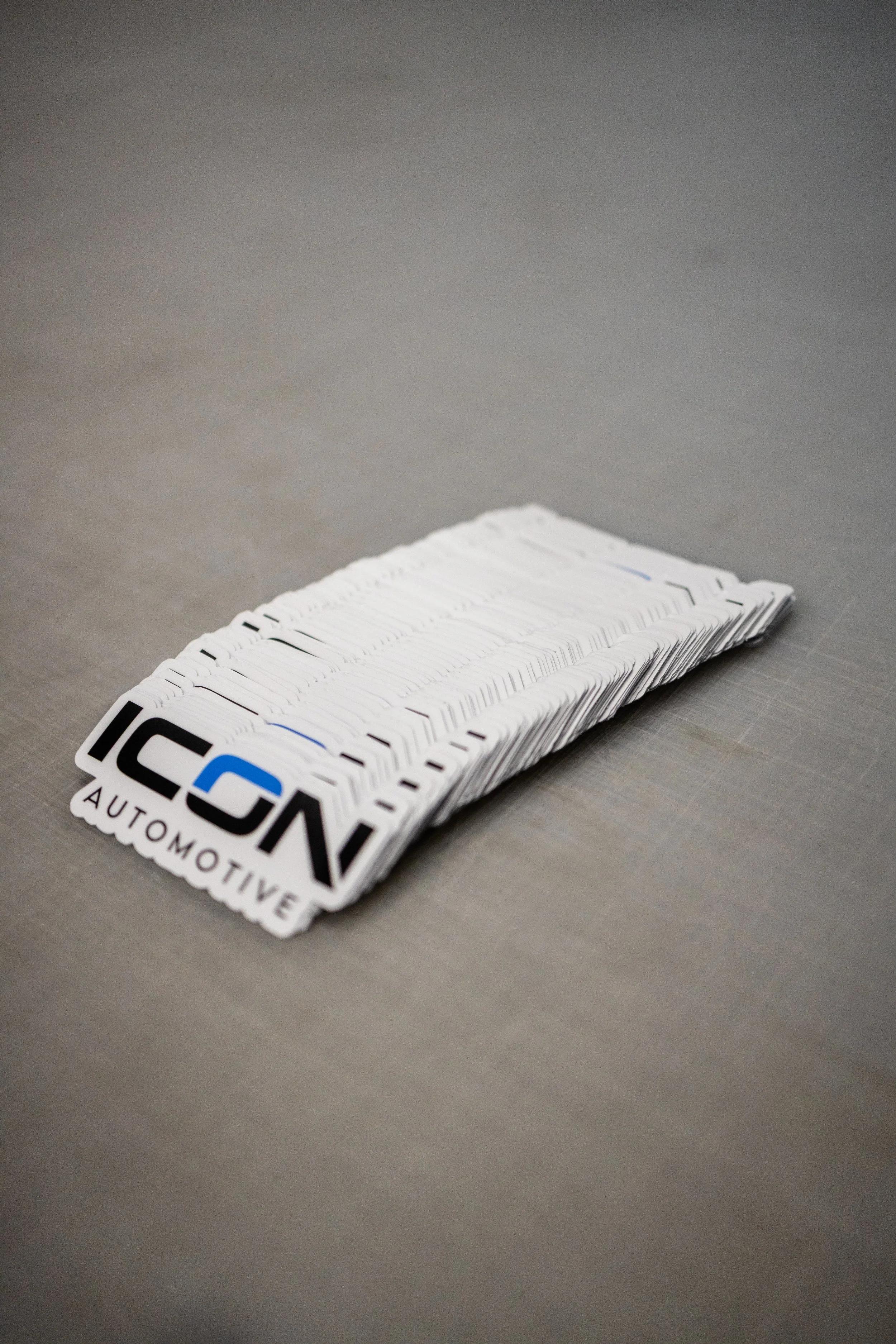 A stack of branded automotive corner stickers on a gray surface.