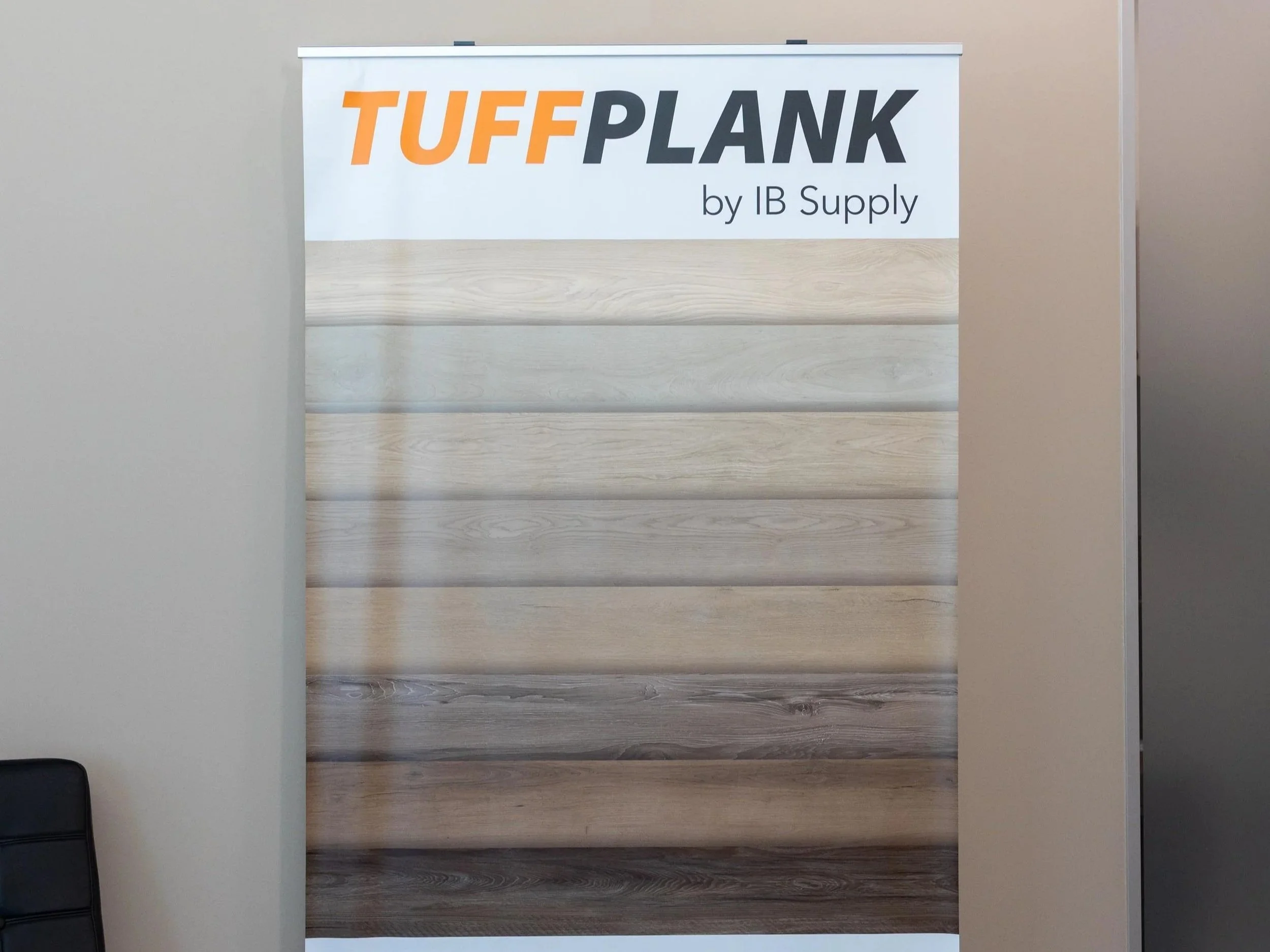 A display board showcasing various wood plank samples with a banner reading 'TUFF PLANK by IB Supply' at the top.
