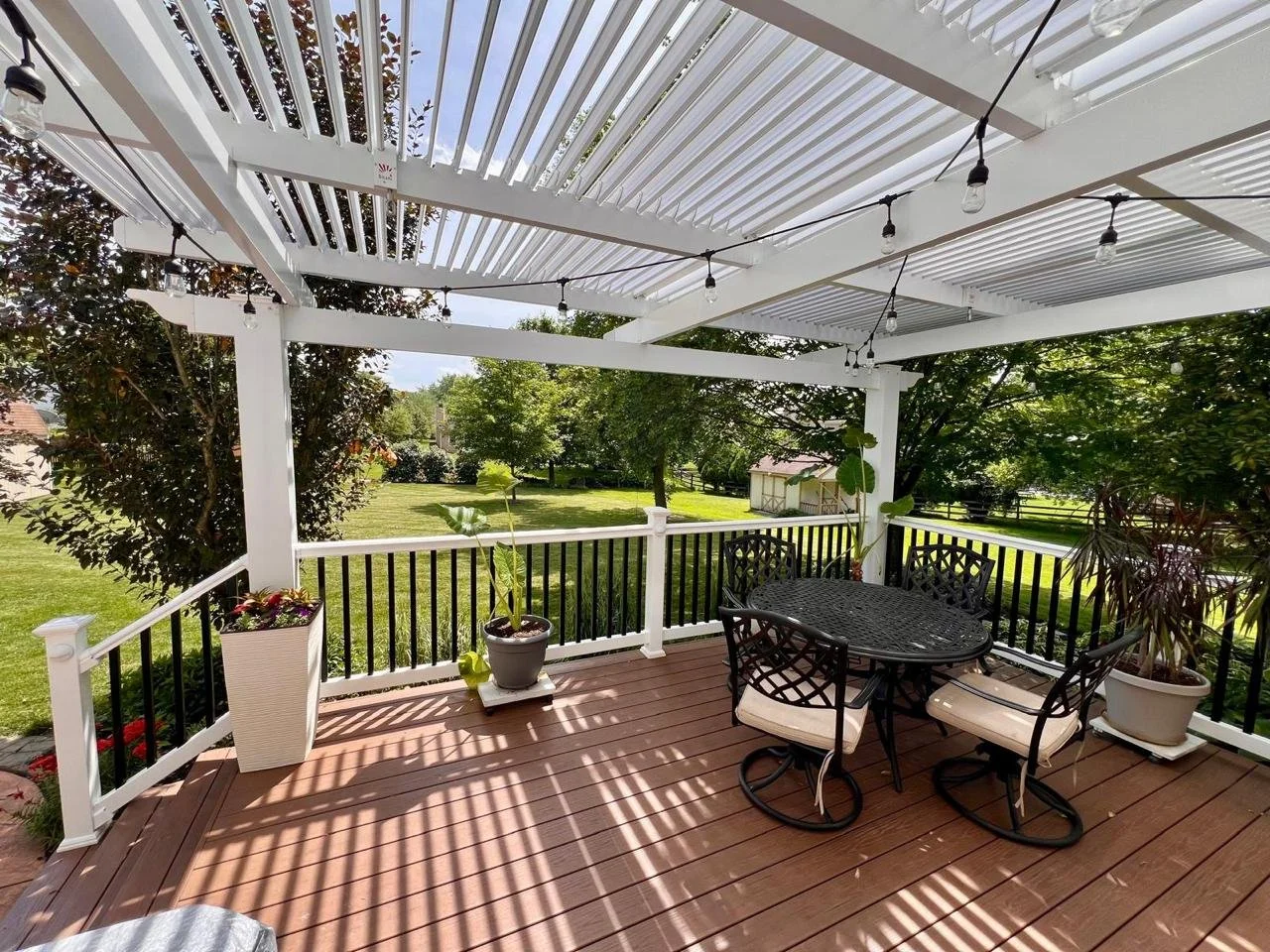 Patio Covers Ohio - White louvered patio cover in an Ohio backyard with string lights and a dining setup designed for everyday outdoor use.