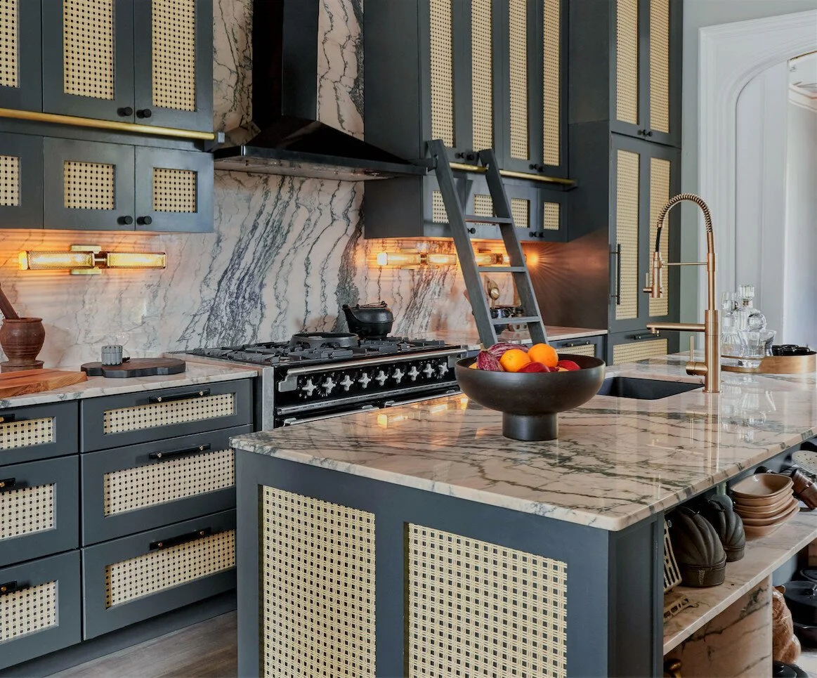 Kitchen with trad and modern elements, including high end blue cabinets, marble countertops, and a marble backsplash.