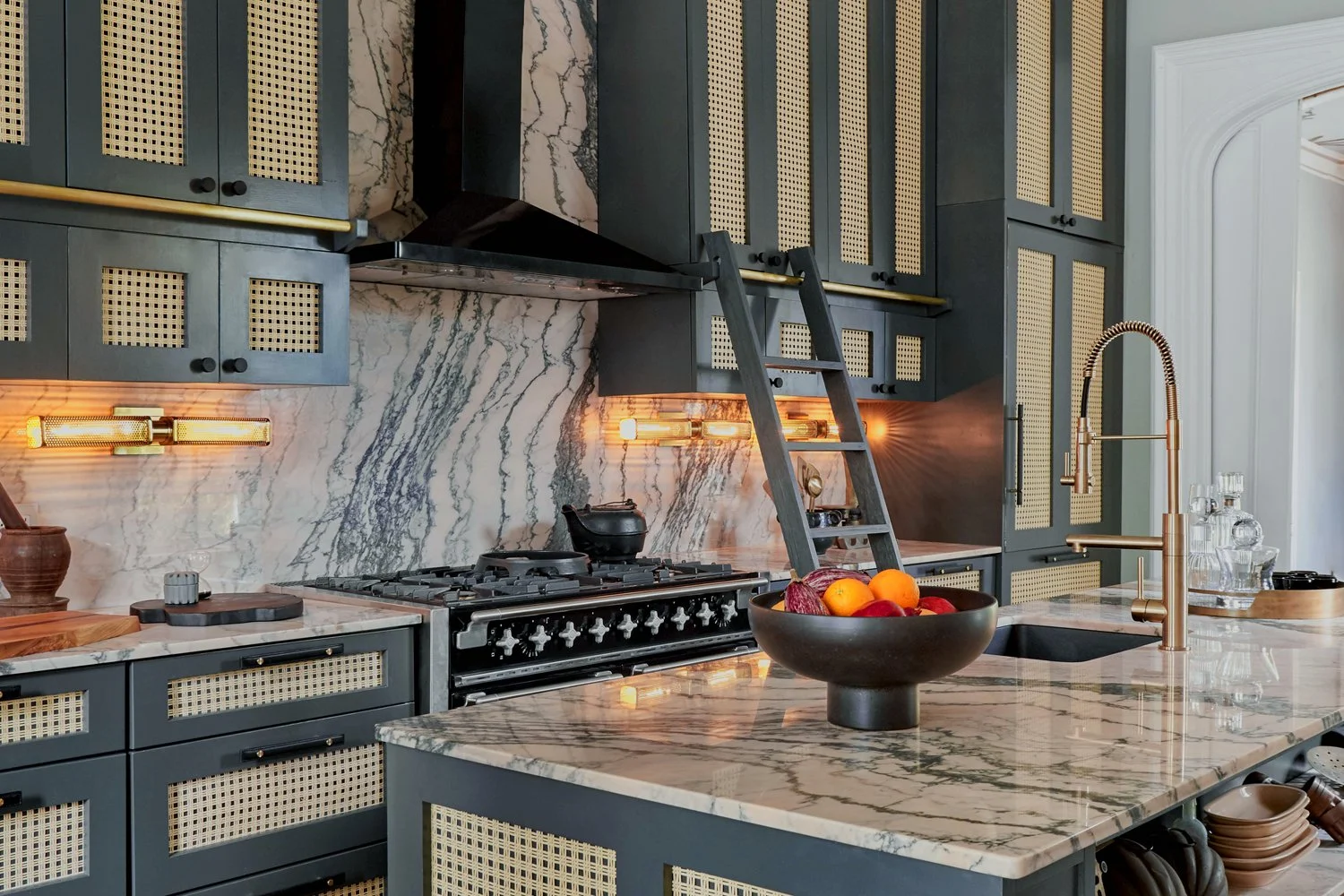 Kitchen with trad and modern elements, including high end blue cabinets, marble countertops, and a marble backsplash.