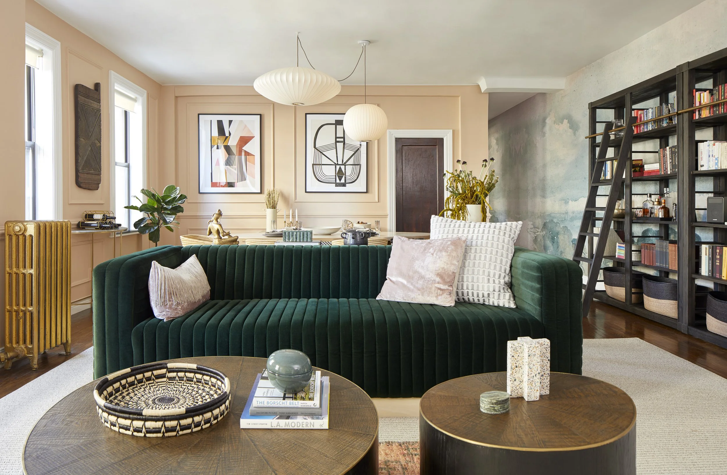 Living room with a green velvet sofa, peach walls and abstract art.