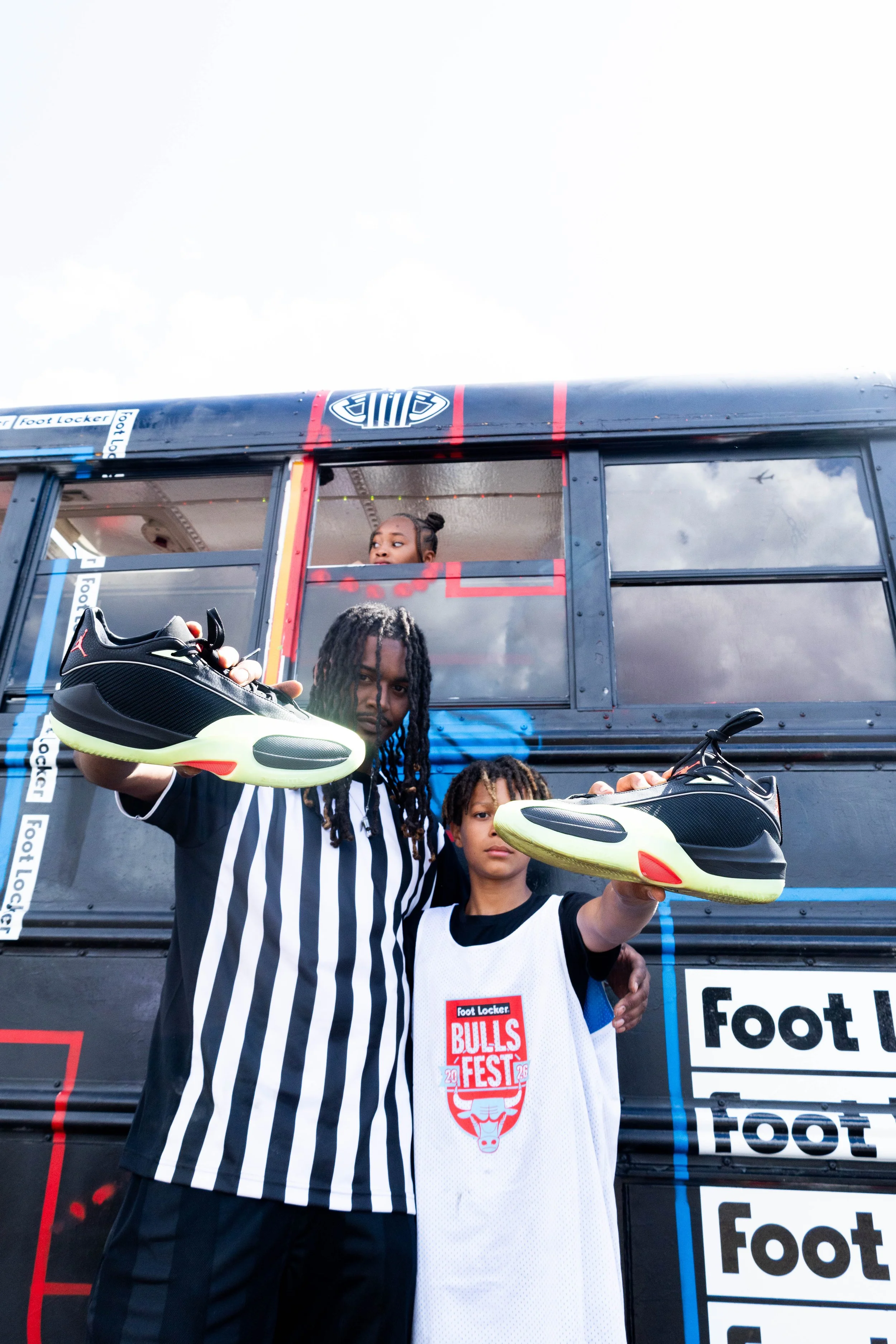 A Foot Locker striper and a youth athlete pose at the Hoopbus for a photo with a pair of shoes. 