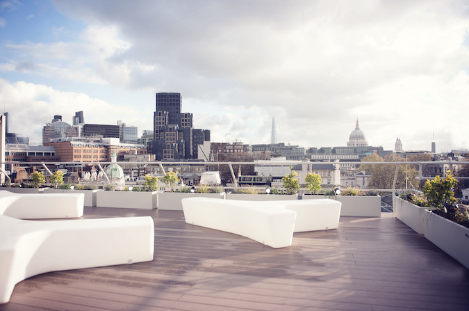 Rooftop terrace overlooking the London skyline with white outdoor seating and planters, central London office building