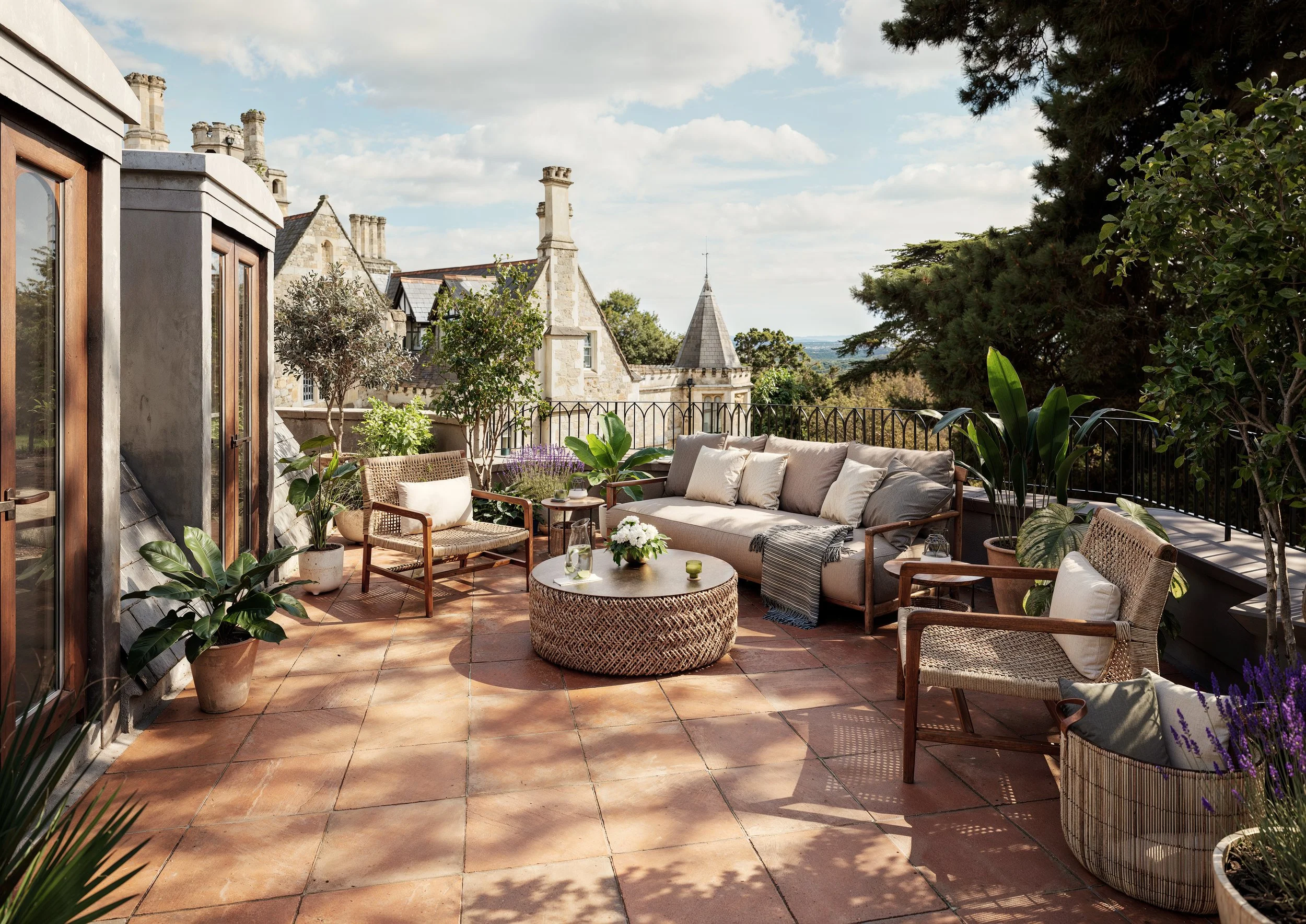Outdoor rooftop patio with seating area including sofas, armchairs, and a round woven coffee table, surrounded by potted plants and overlooking historic buildings and trees listed building  flat conversion penthouse interior design