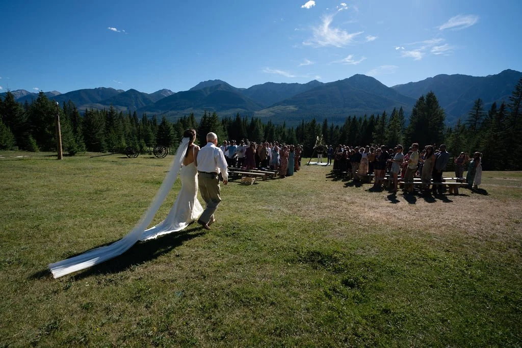 Bride walking in outdoor wedding ceremony with mountains in background