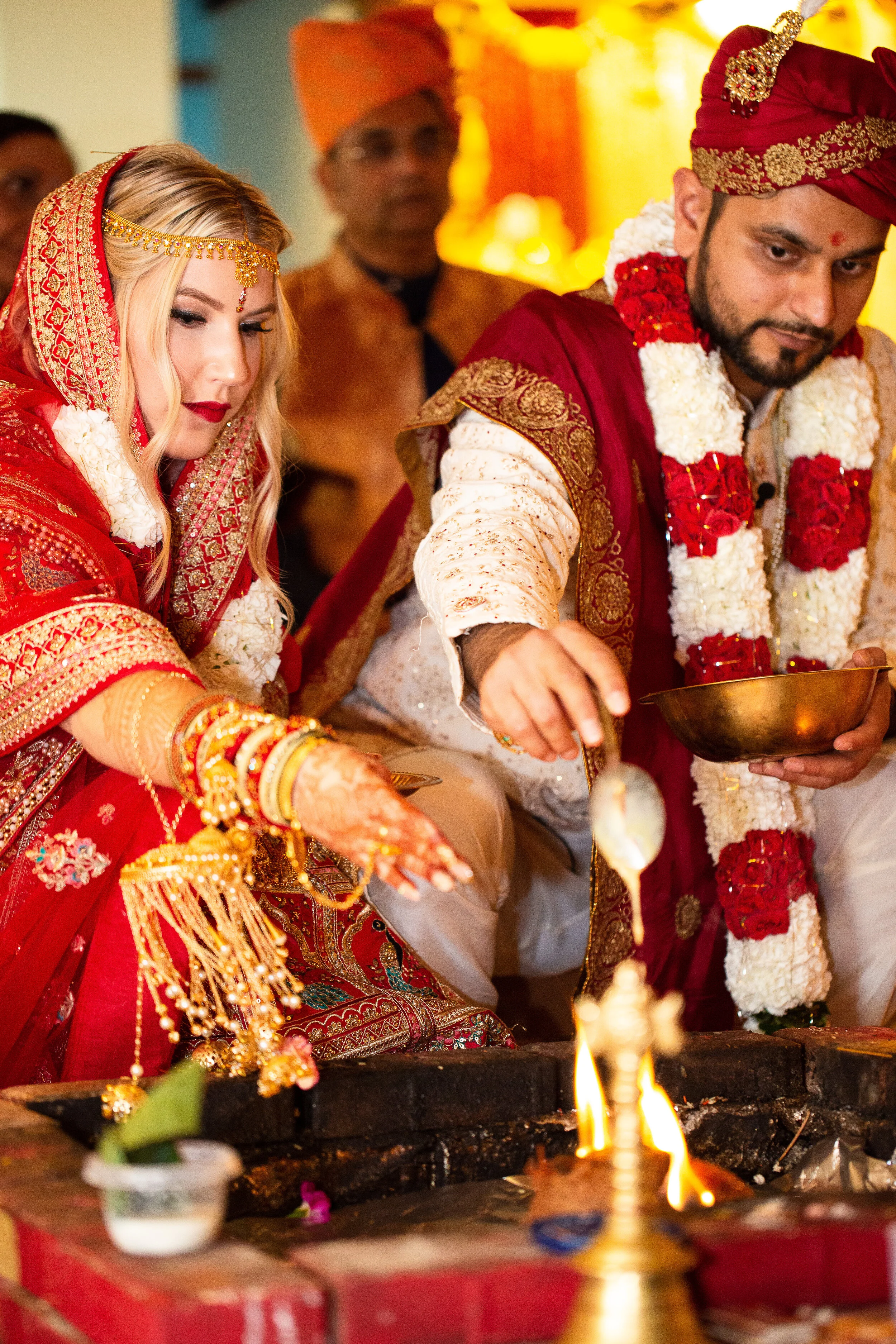 A couple in traditional Indian wedding attire performing a ceremony.