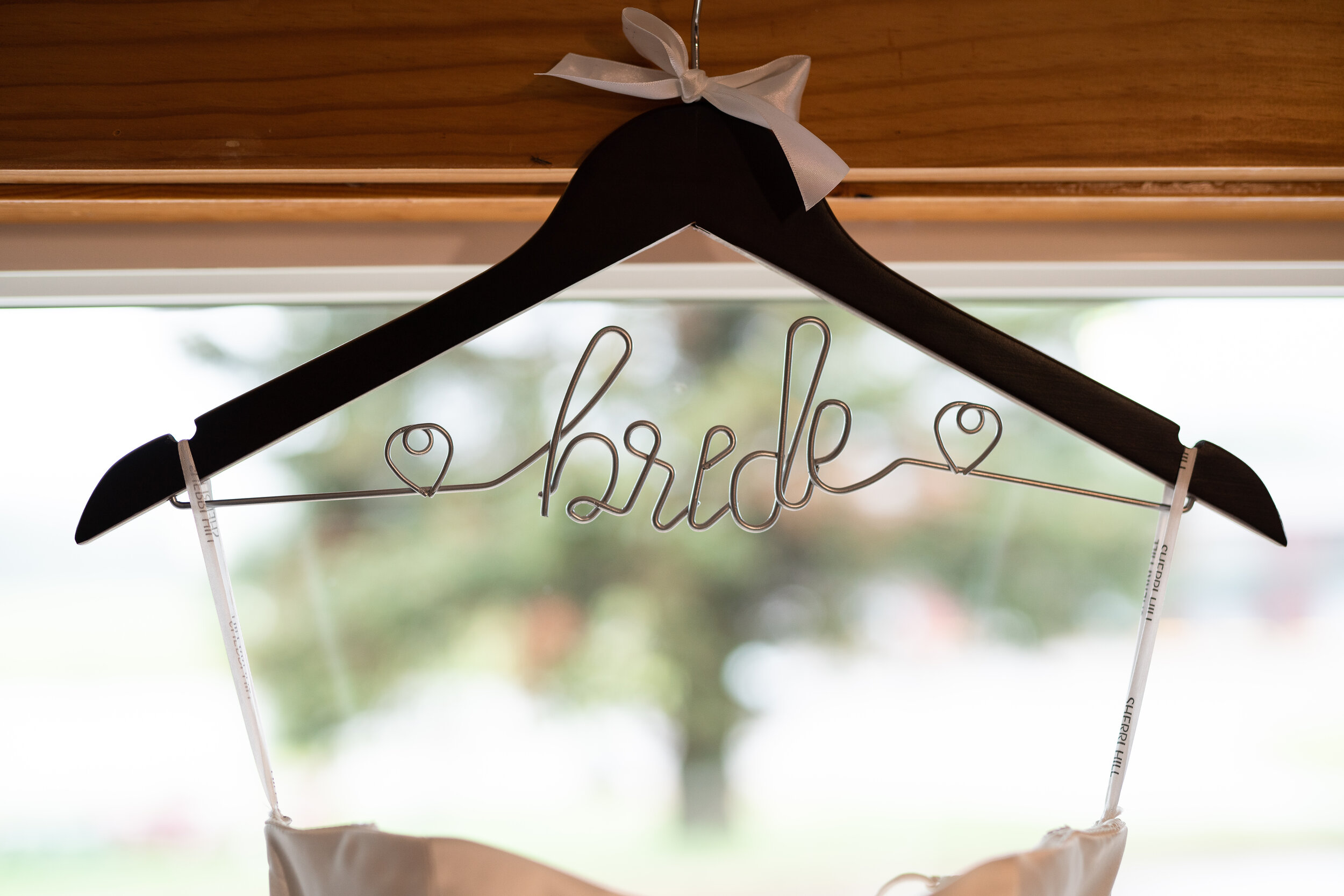 Wedding dress hanger with 'bride' in wire lettering, featuring a white ribbon.