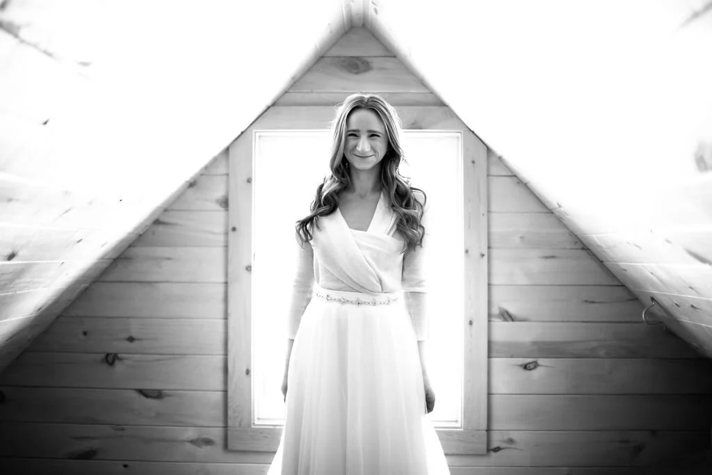 Black and white photo of a bride in a wood-paneled room.