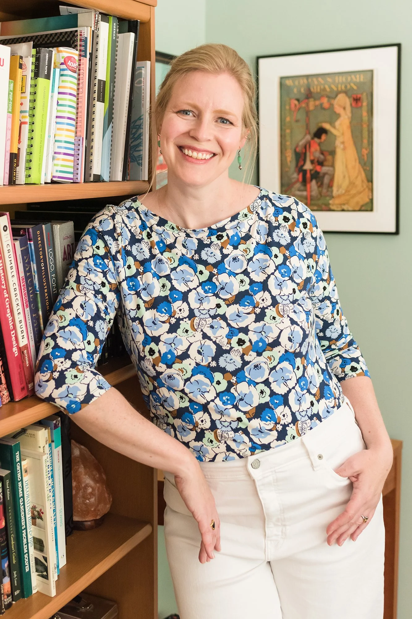 Jenni Ohnstad, nonprofit branding strategist, wearing a floral top leaning against bookshelf in Nashville, TN