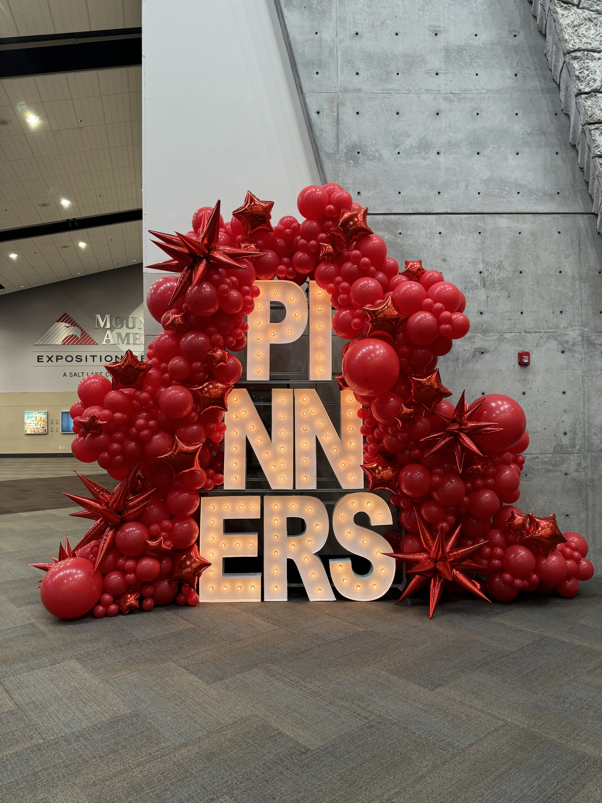 Eye-catching display at Pinners Conference: Alphalit marquee letters forming 'pinners' enclosed in a striking monochromatic balloon installation in vibrant Pinterest red. Mylar star balloons add a touch of whimsy to the dynamic arrangement.