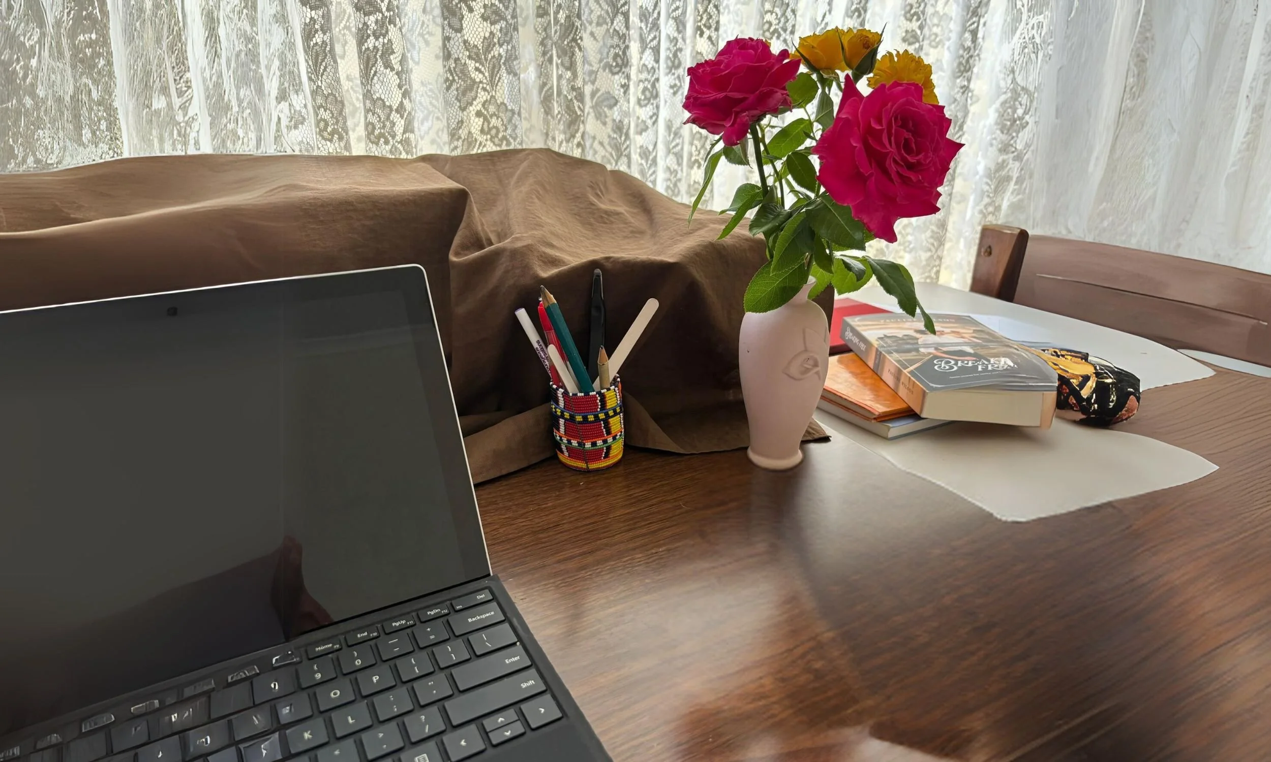 writing desk with laptop pen holder and vase of roses