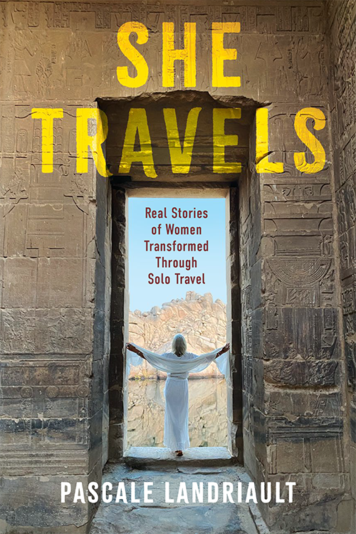 View of the back of a woman dressed from neck to toe in gauzy white fabric in an Egyptian monument. She Travels is written in yellow across the top. By Pascale Landriault.