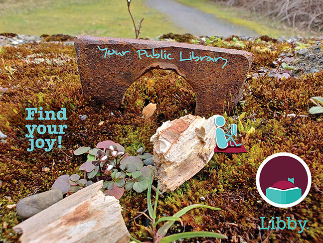 A moss covered rock with a rectangular iron eye. Your Public Library is written across the iron arch, an illustrated person reading a book leans against a small piece of wood by the library, and the image says, "Find your joy!" with the Libby logo.