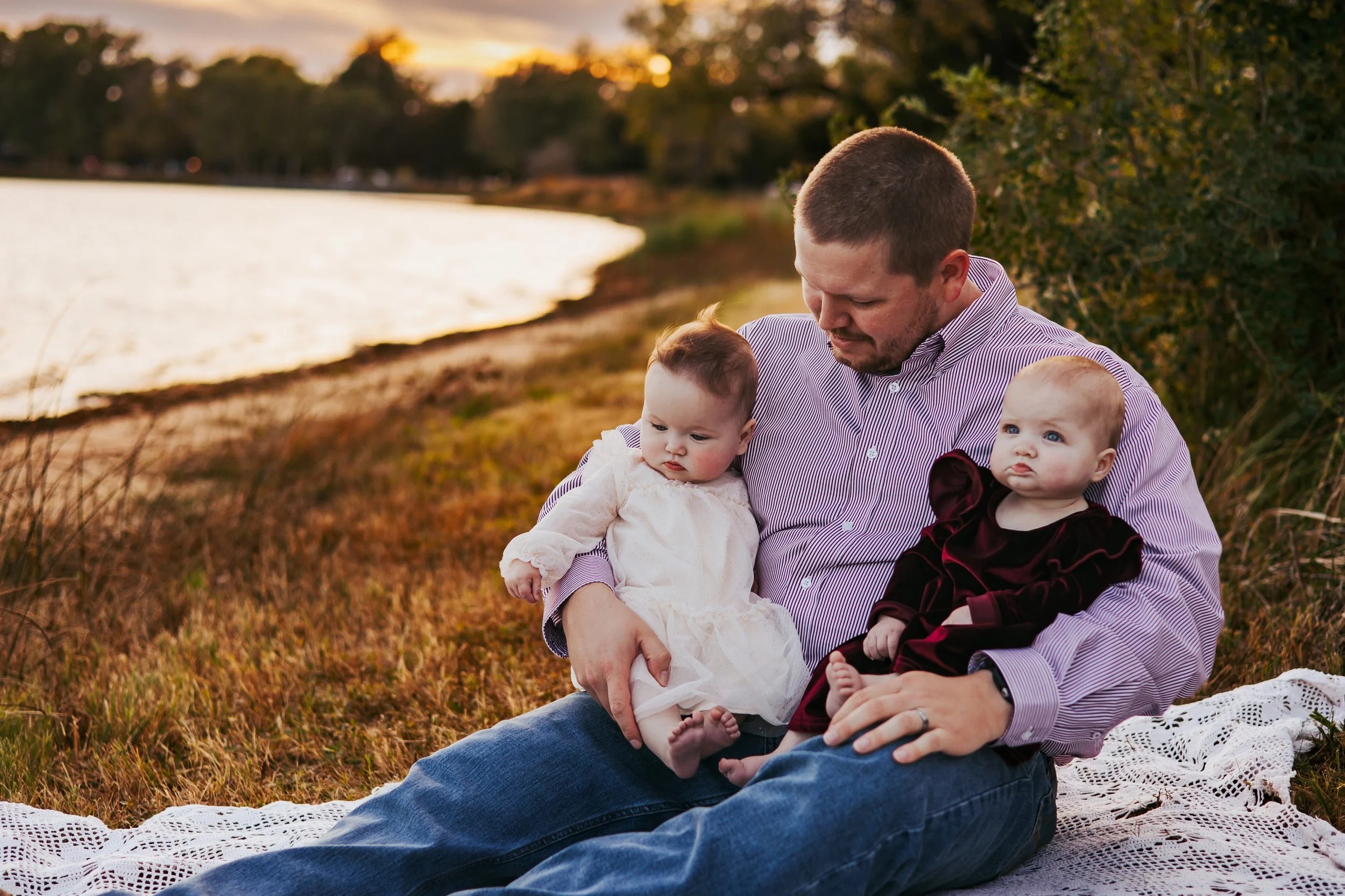 Dad cuddling twins during a relaxed family photo session by river in Nebraska
