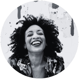 Black and white photo of a woman with curly hair smiling and laughing.