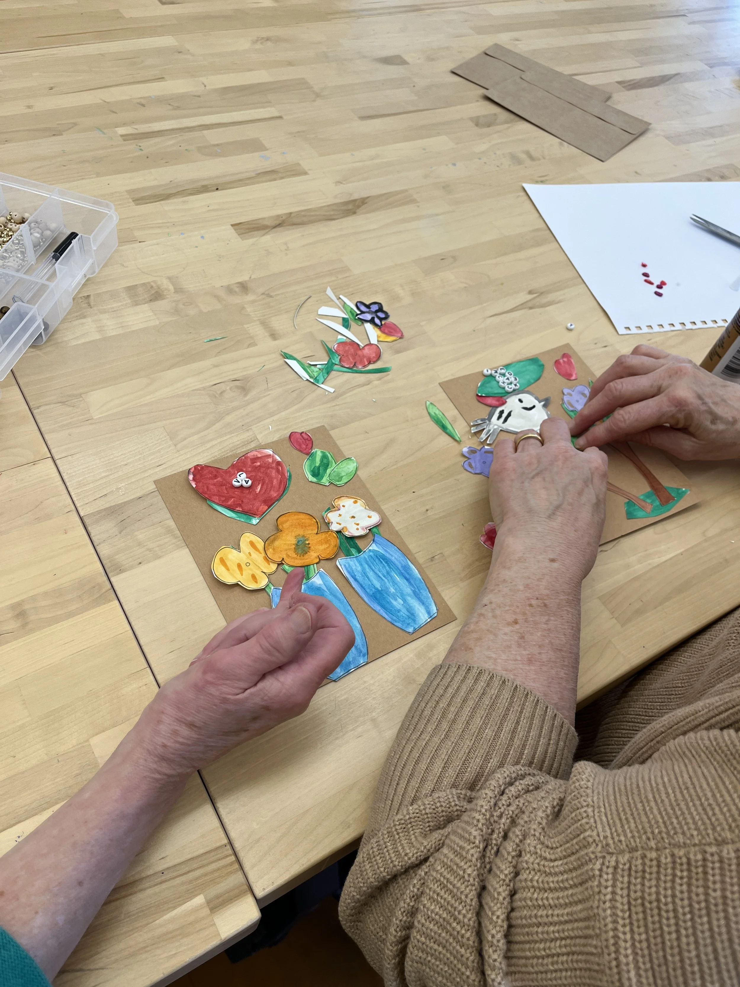 two individuals hands creating and organizing images on brown paper
