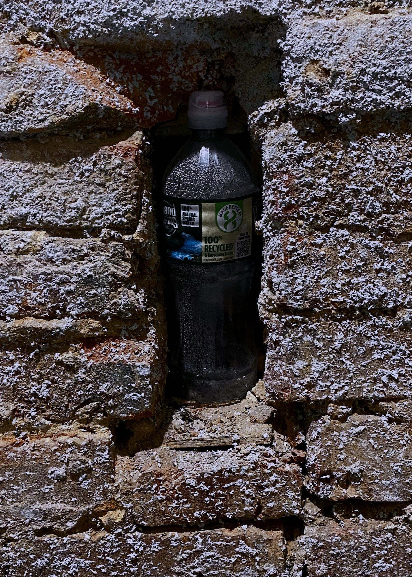 220628.A.02.N.01 - Water Bottle Placed in What Was a Wood Floor Joist Pocket with Flecks from Spray Fireproofing on the Bricks.