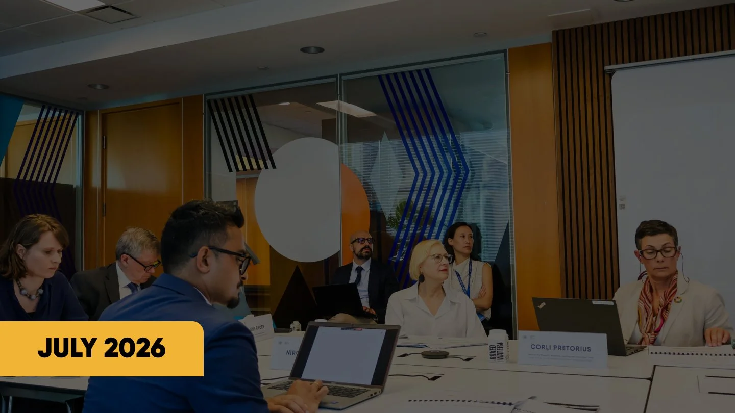 Business meeting in a conference room with attendees using laptops and a July 2026 date graphic