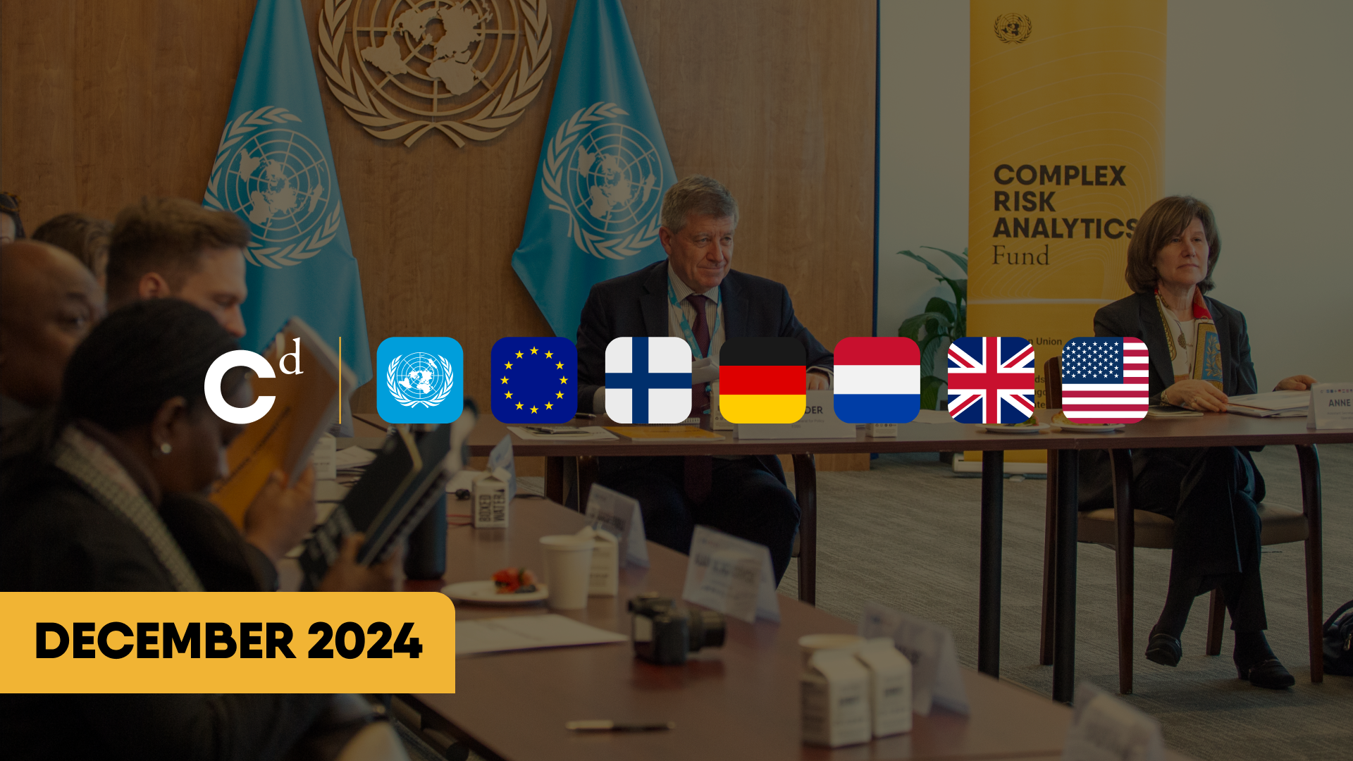 Meeting room with United Nations flags, a man and a woman seated at a table, yellow banner with 'Complex Risk Analytics Fund', and overlay icons including the European Union and American flags, December 2024.