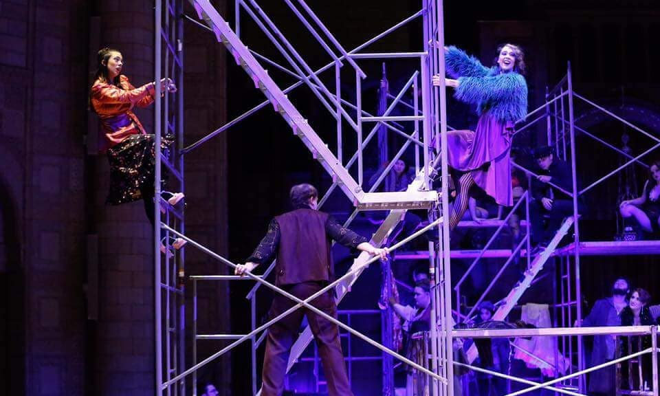 Performers on scaffolding stage during theatrical performance