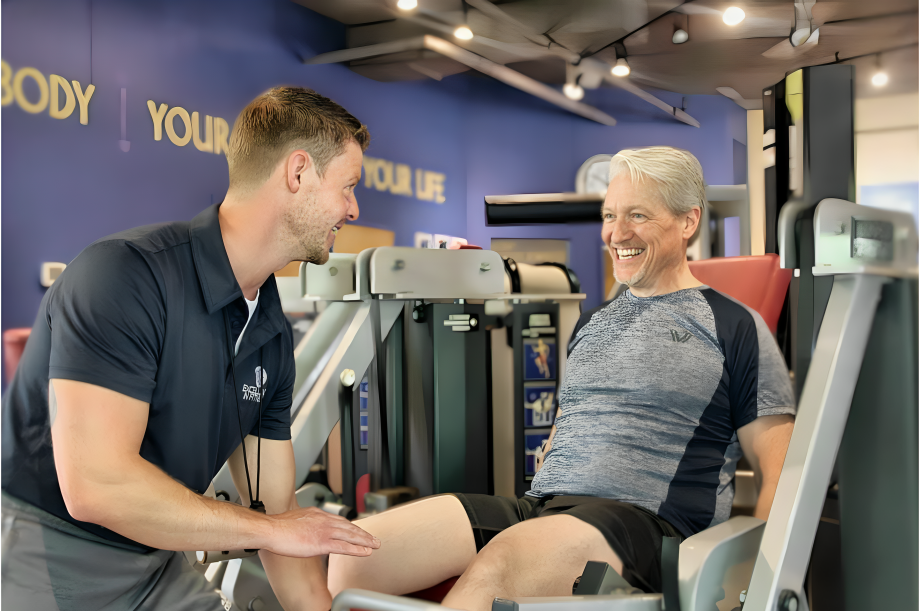 Personal trainer providing one-on-one coaching to help a client build strength and confidence at Excellence In Fitness