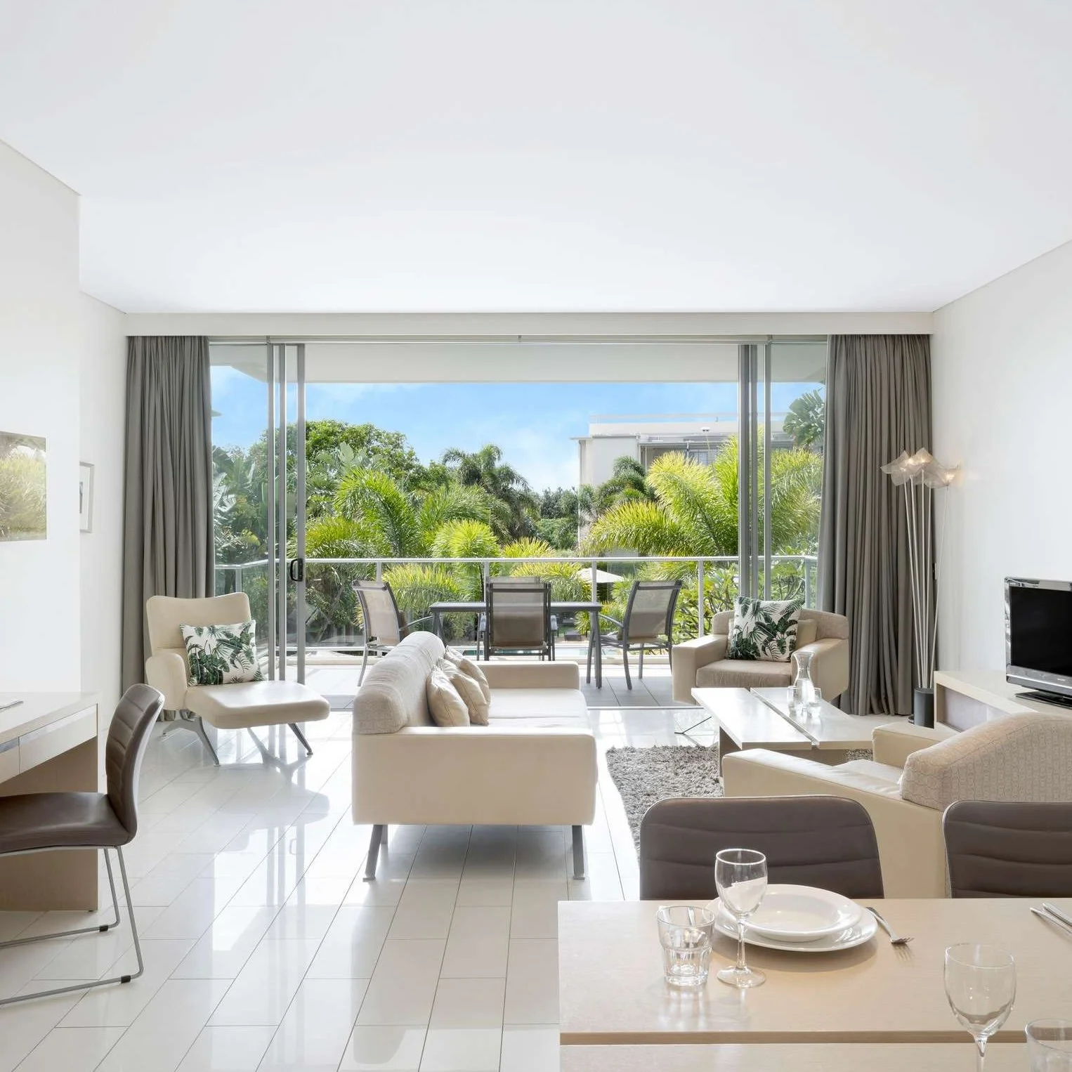 A stunning sunset cityscape with a river, lush greenery, vibrant pink bougainvillea in the foreground, and modern skyscrapers in the background.