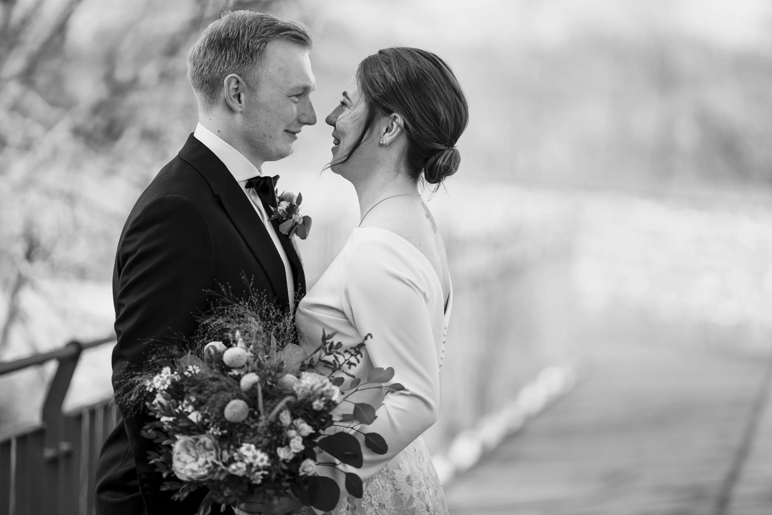 Brautpaar auf Schloss Romrod steht sich mit Blumenstrauß gegenüber und lächelt sich an, schwarz weiß Foto