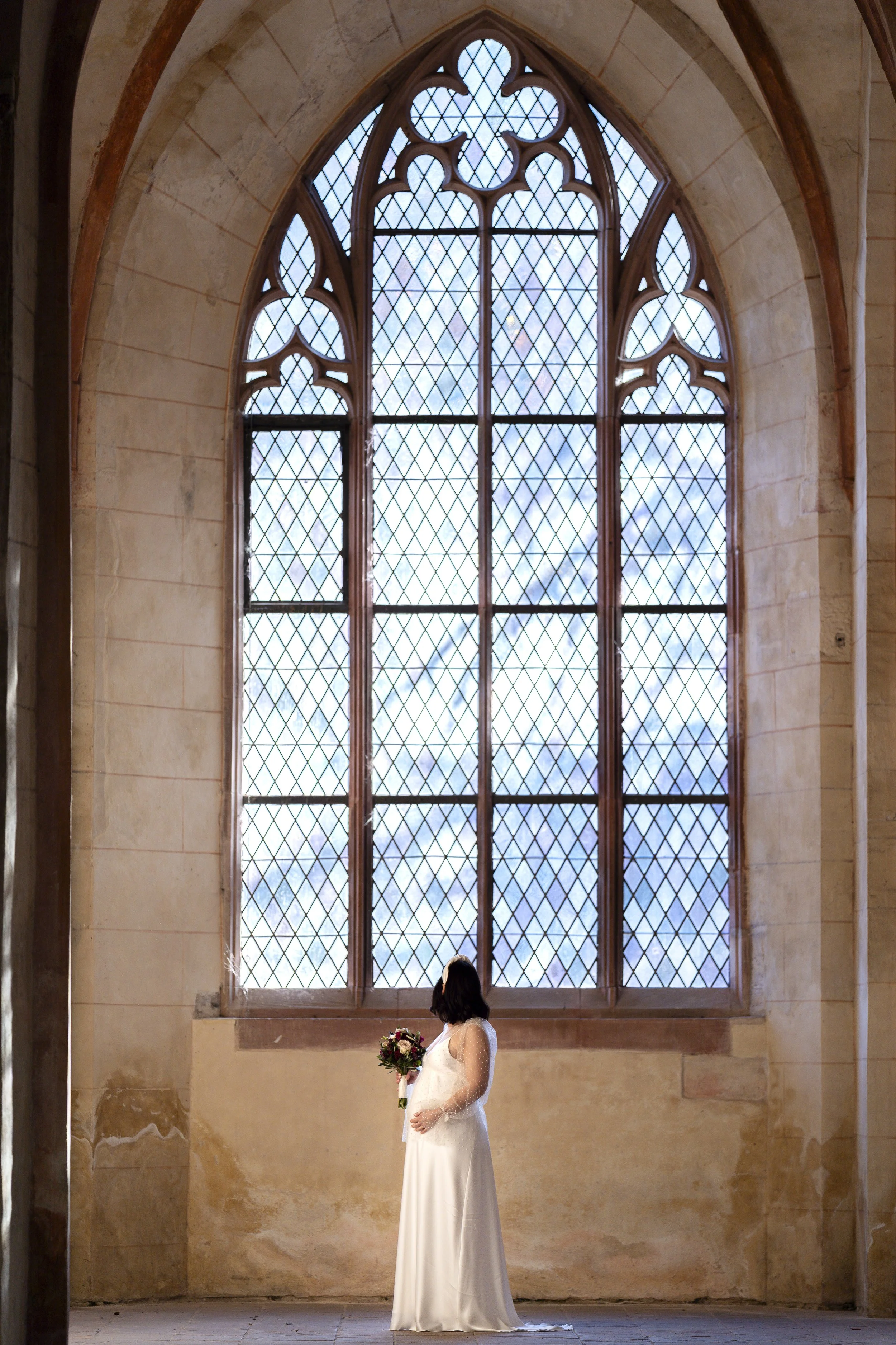 Schwangere Braut in der Basilika des Kloster Eberbach im Rheingau vor großem Fenster