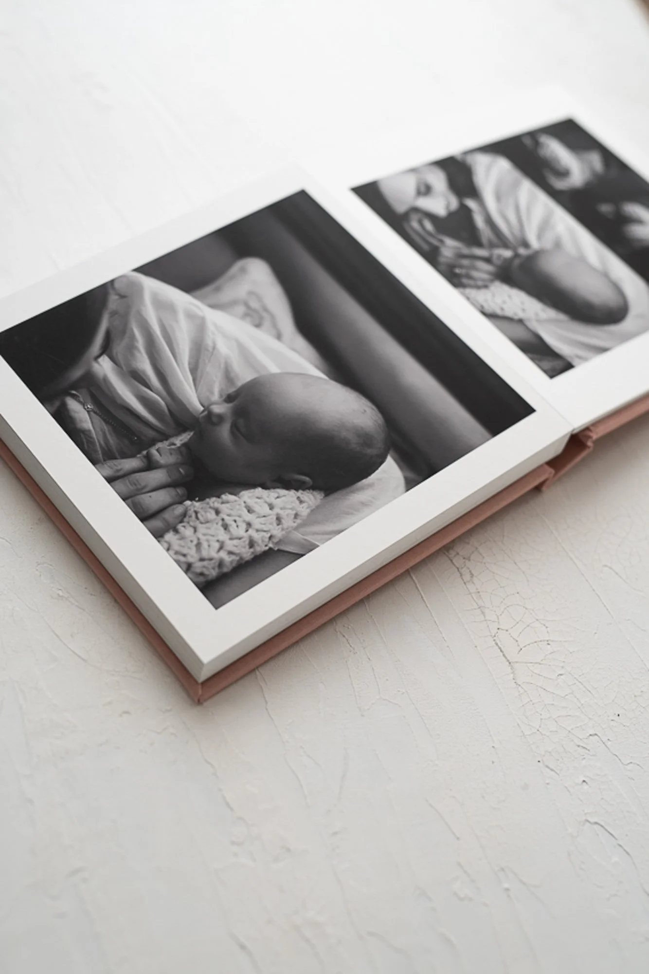 Fine art newborn album open to black and white photographs of mother holding newborn
