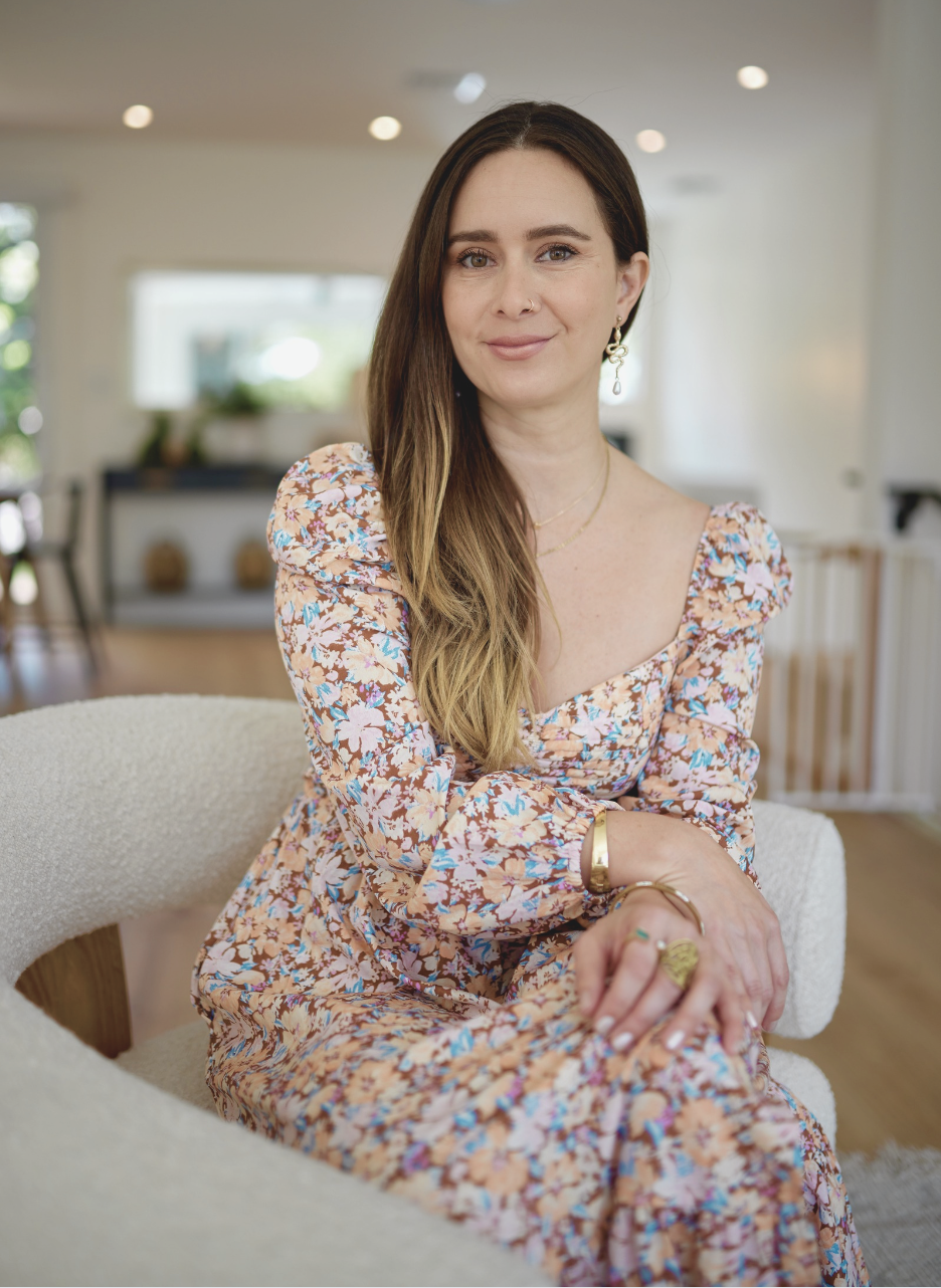 Paula sitting in a soft white chair in a bright home