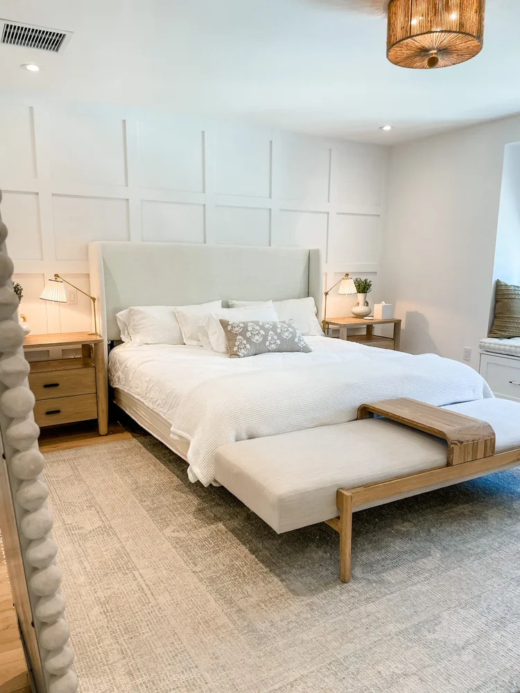 A calm bedroom with a paneled wall and a woven bench