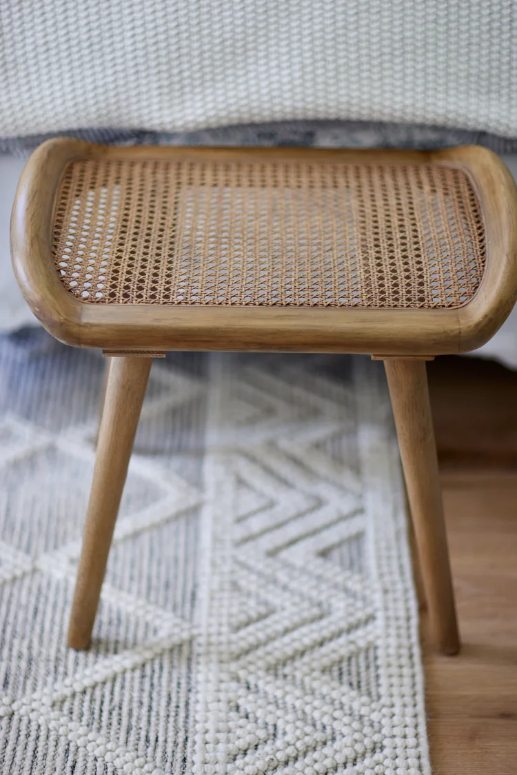 A cane stool on a patterned rug