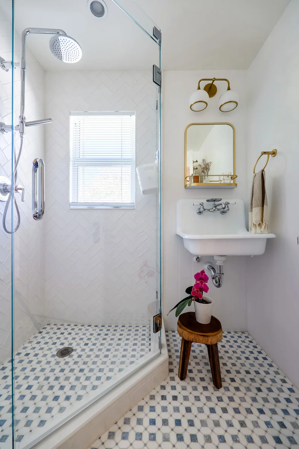 A bright bathroom with patterned floor tile and brass details