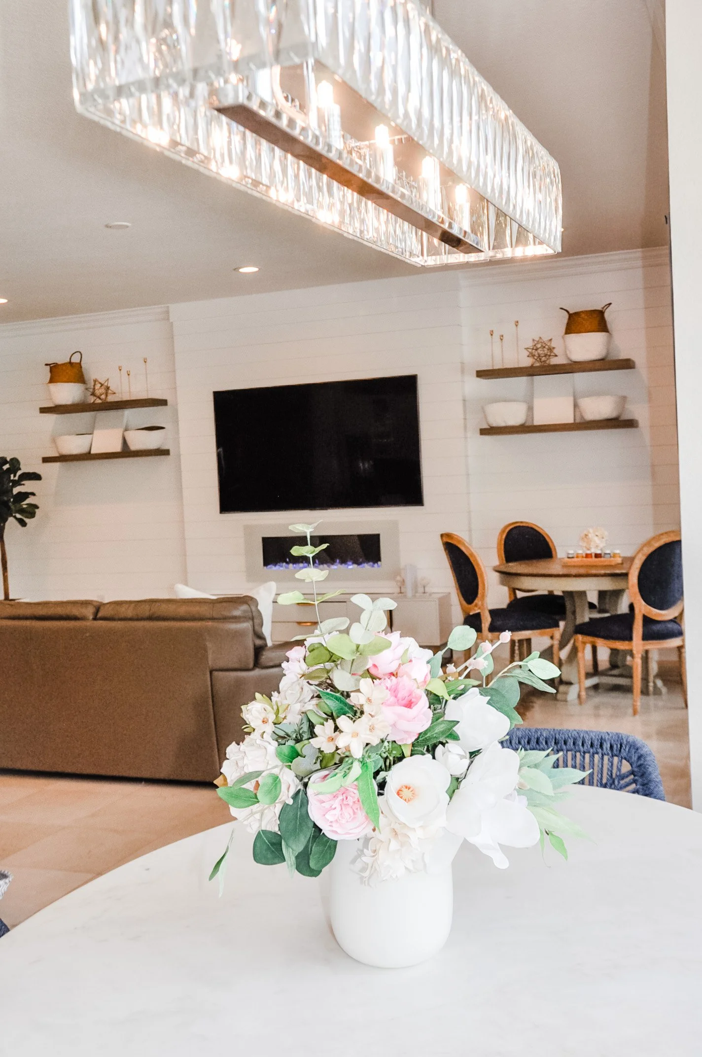 An open living and dining room with floating shelves and fresh flowers