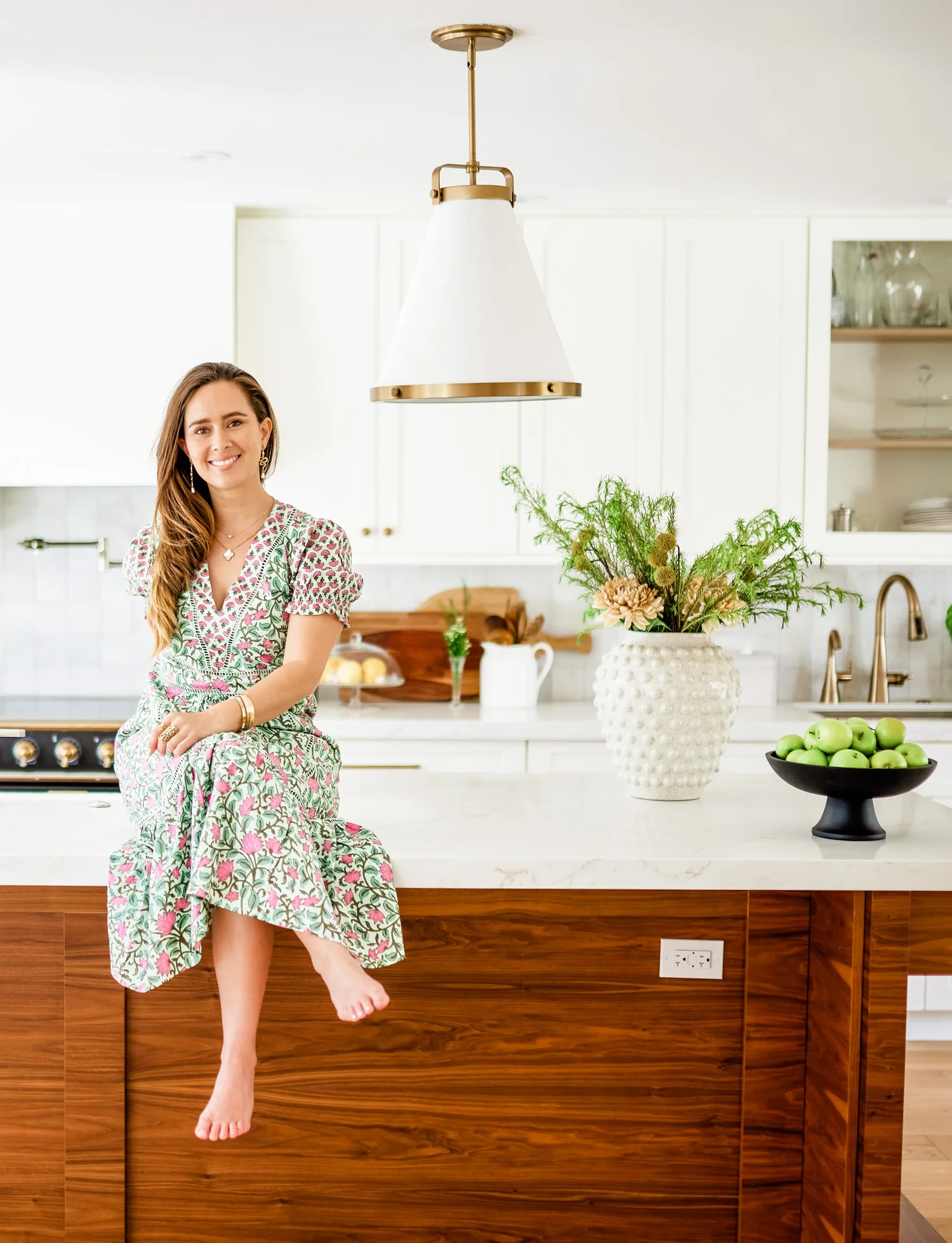 Paula sitting on a kitchen island in a bright, white kitchen