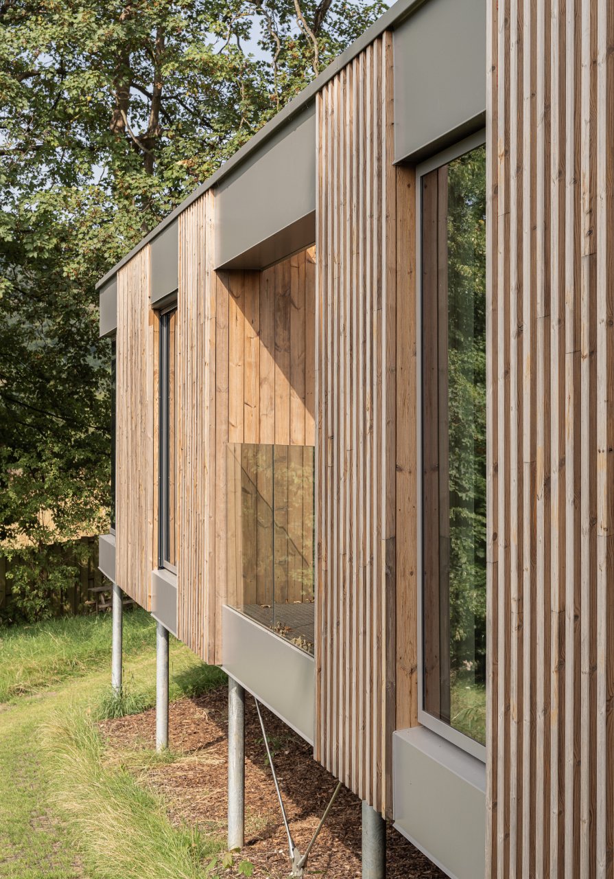 Timber and zinc clad new dwelling suspended lightly over the existing hillside