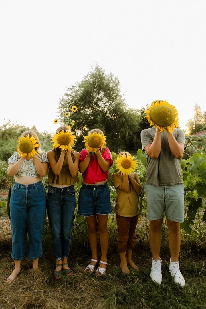 kids holding sunflowers in front of their face 