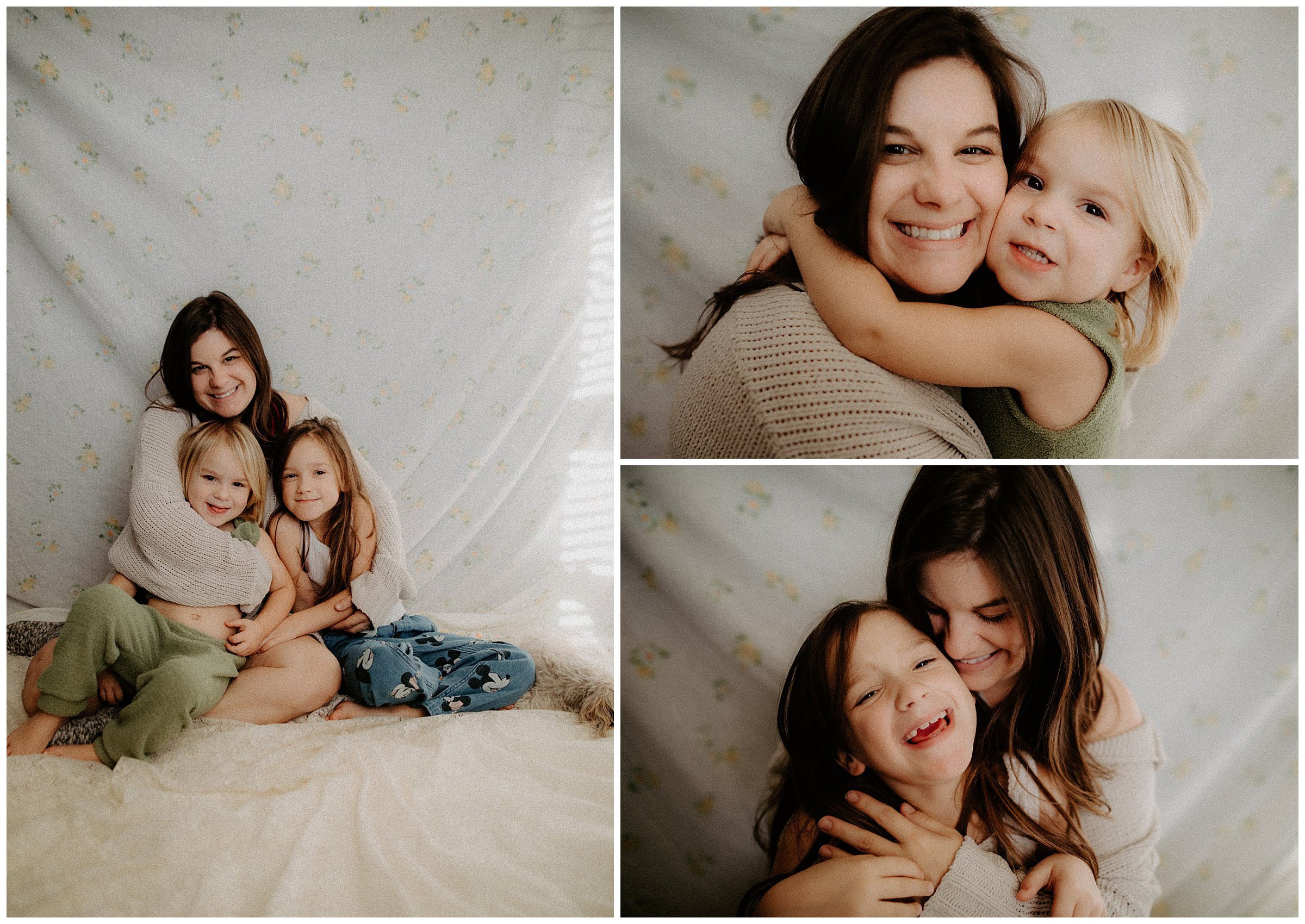A woman with two young girls in a cozy indoor setting. The woman and the girl on the right are hugging and smiling, while the girl on the left is sitting close with a playful expression. The background features light-colored, floral-patterned fabric.