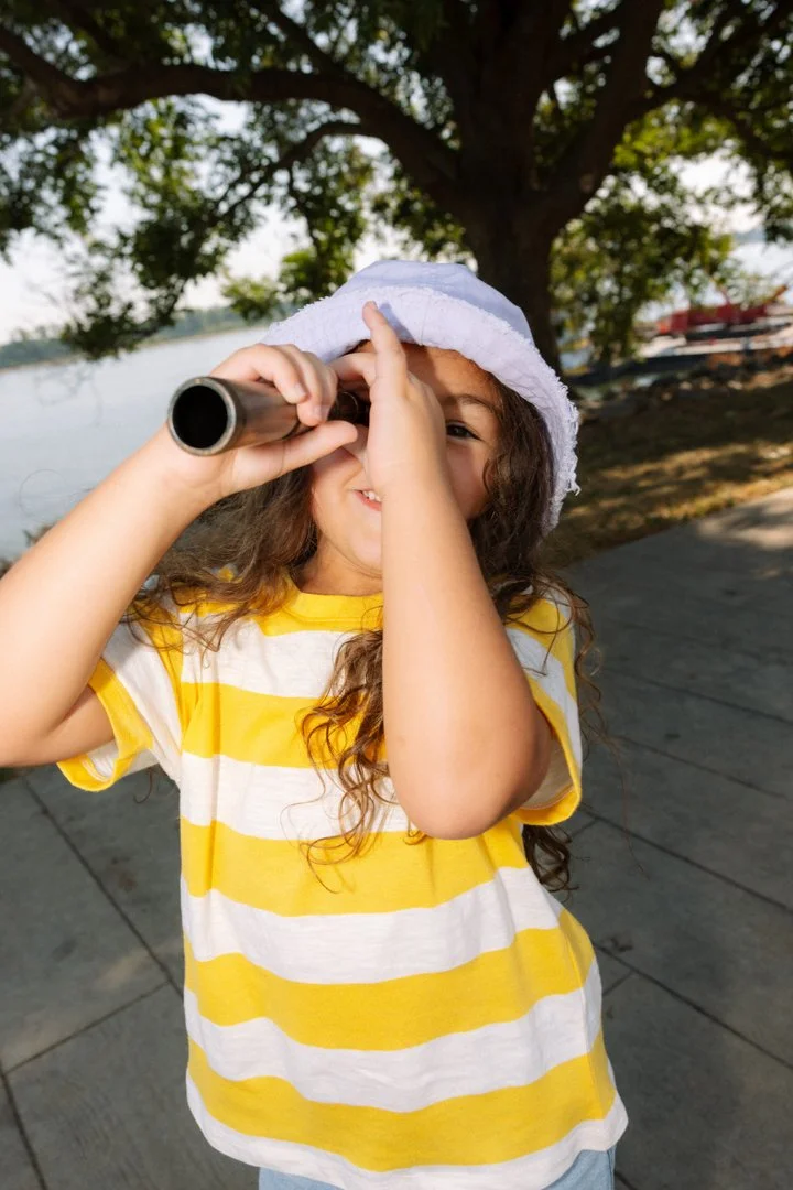 kid holding telescope looking at camera
