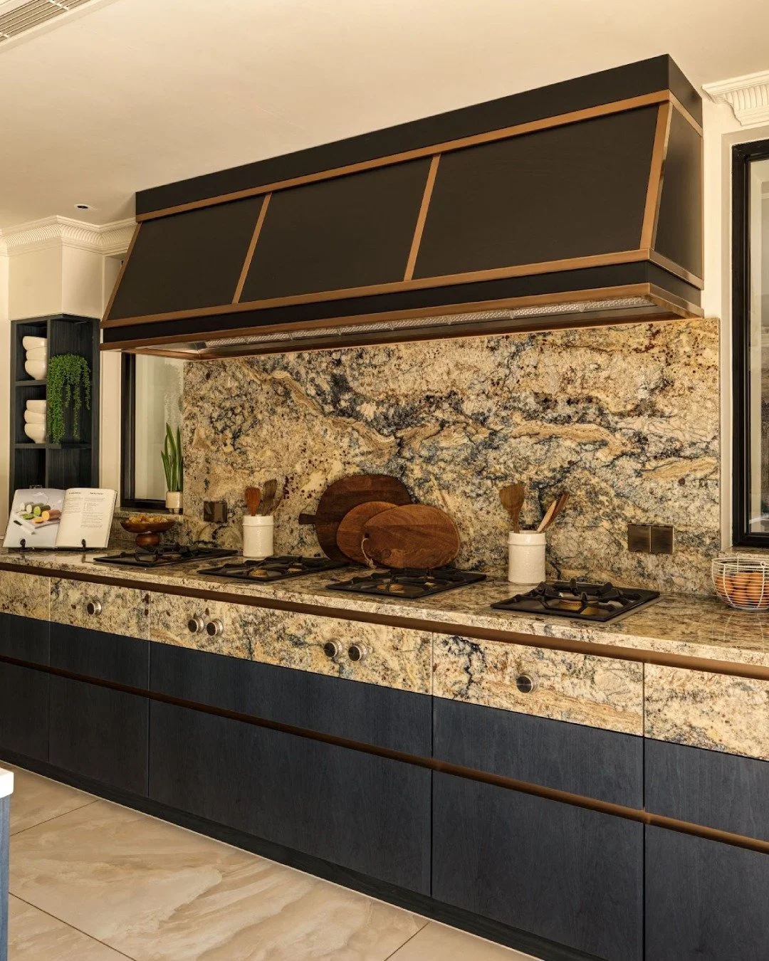 This cooking area is shaped by stone that runs across the worktop and splashback, creating a steady backdrop for everyday use. Storage sits quietly beneath, allowing the texture and movement of the stone to take the lead, while open surfaces leave sp