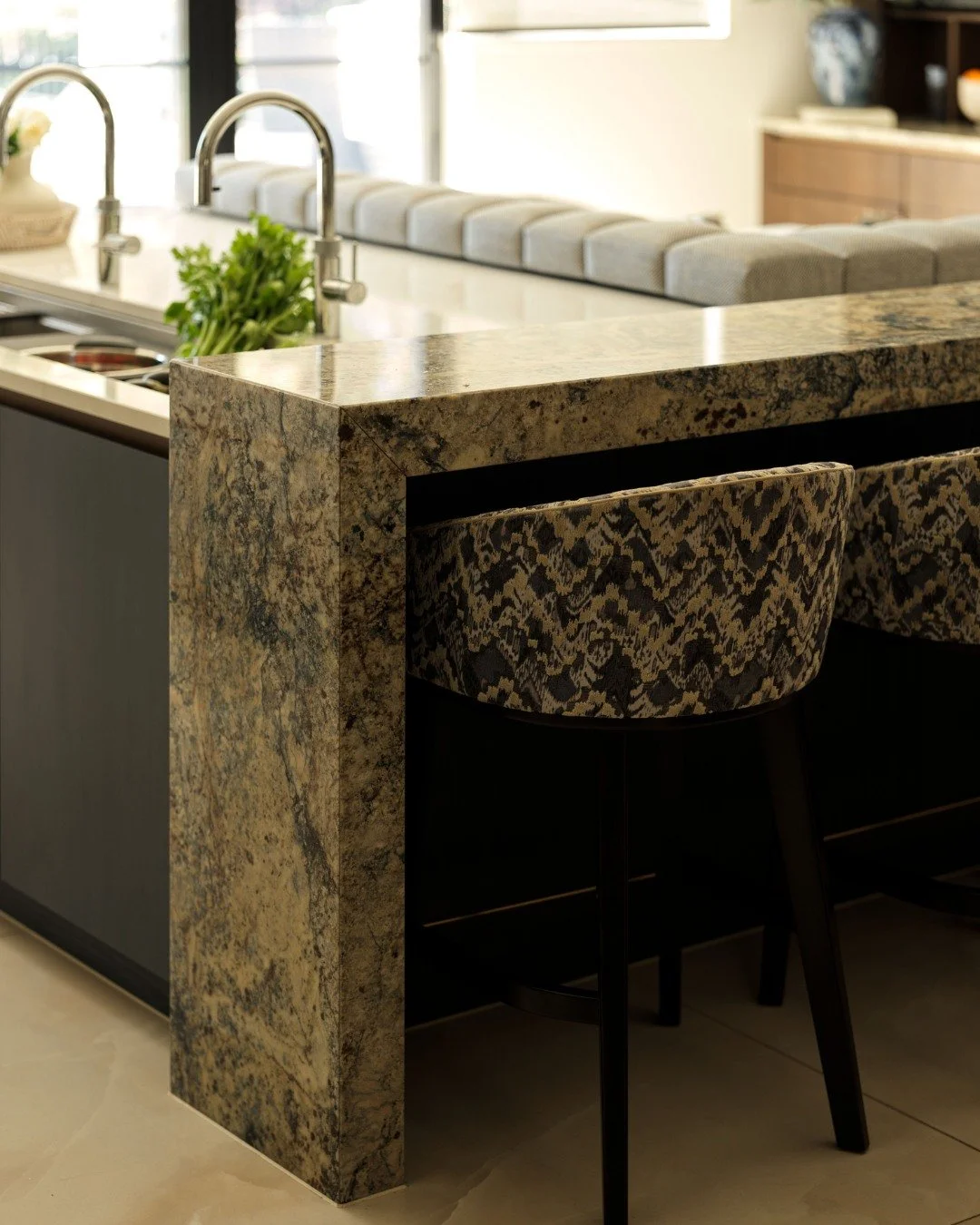The breakfast bar sits at the heart of this kitchen, easily shifting between a space for preparing meals and a relaxed spot to pull up a stool and spend time together. Crafted from stone, it brings a solid, sculpted feel while fitting naturally into 