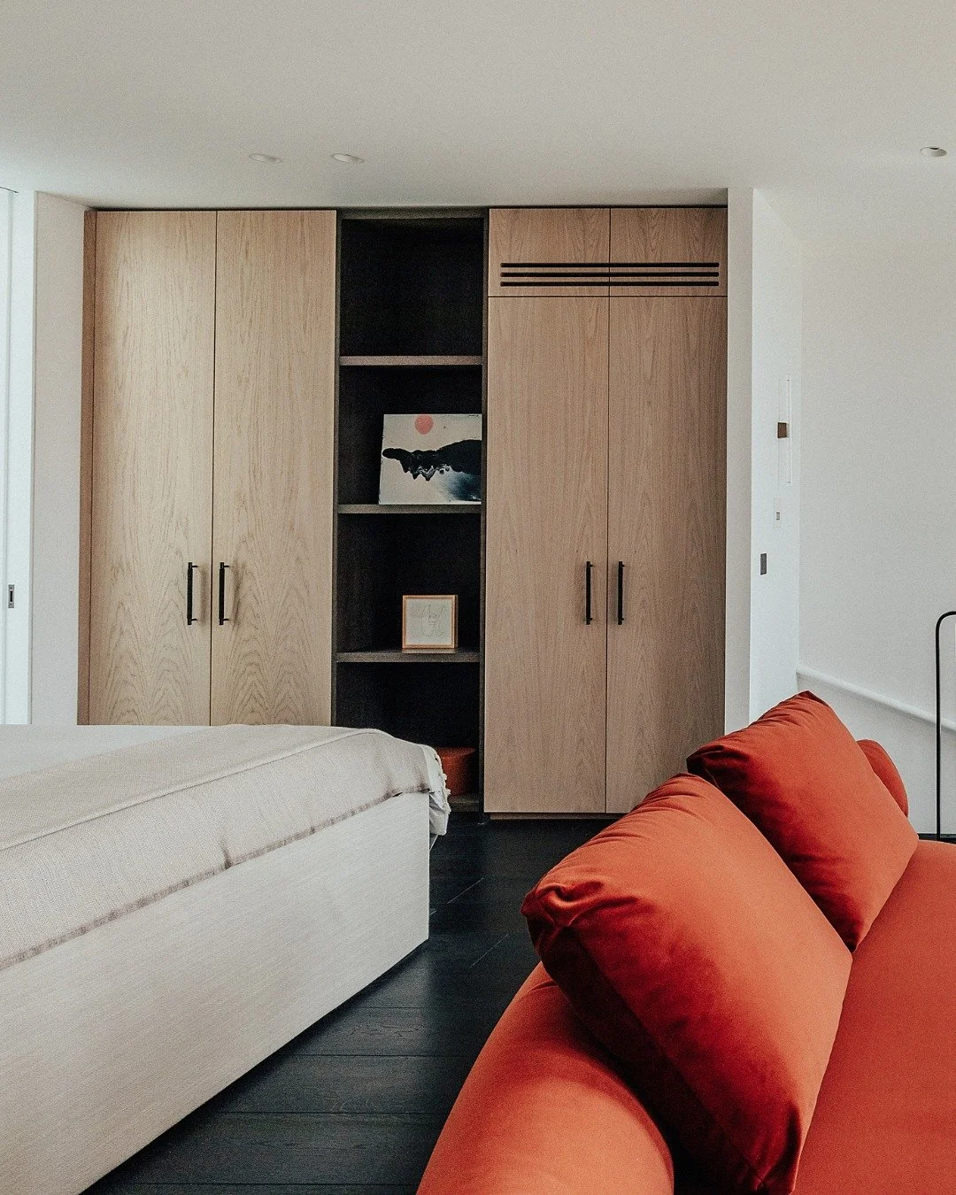 Crown-cut oak wardrobe doors finished in a light bleached stain give this space a more natural feel, while the darker espresso-stained oak internals add depth and contrast. Open shelving keeps everyday essentials easy to reach as the day gets going, 