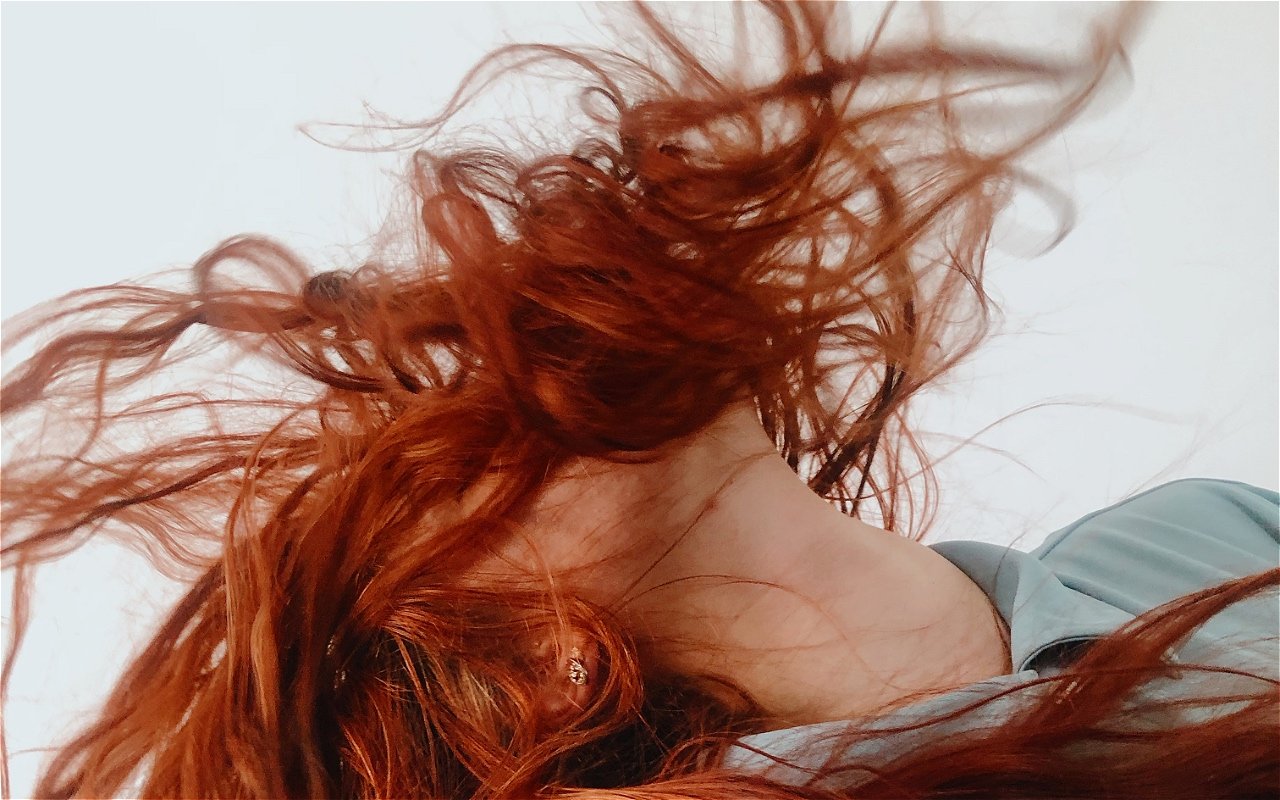 Red hair flying around an upturned face covered by aforementioned hair