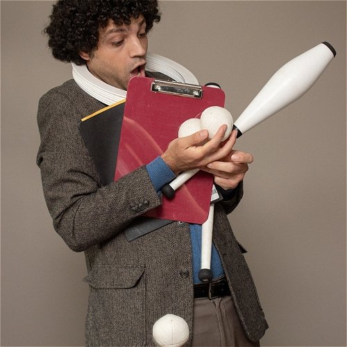 An overwhelmed man juggles his juggling materials and a clipboard