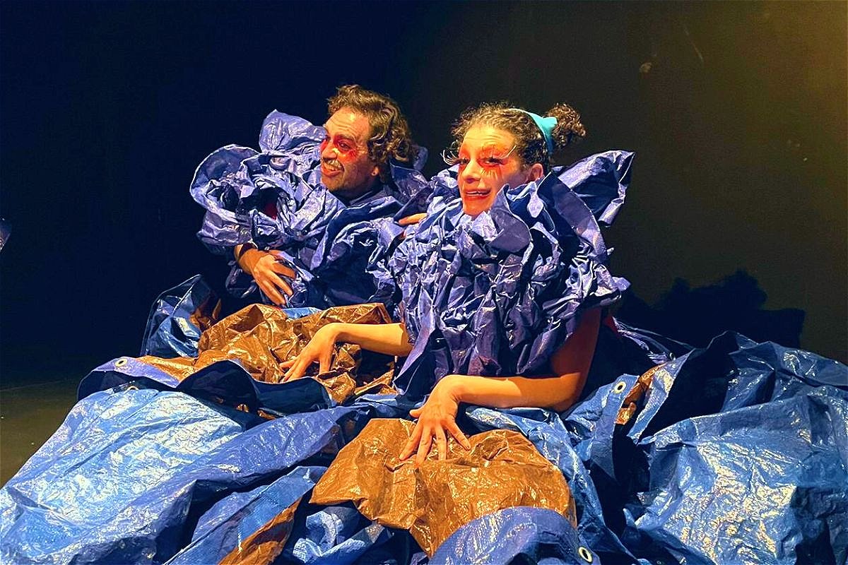 Two people dressed in tarps smile