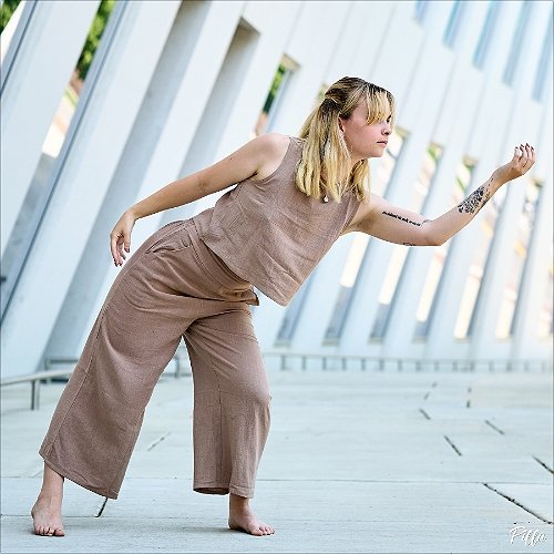 Woman in all tan dances in front of some white leany modern architecture